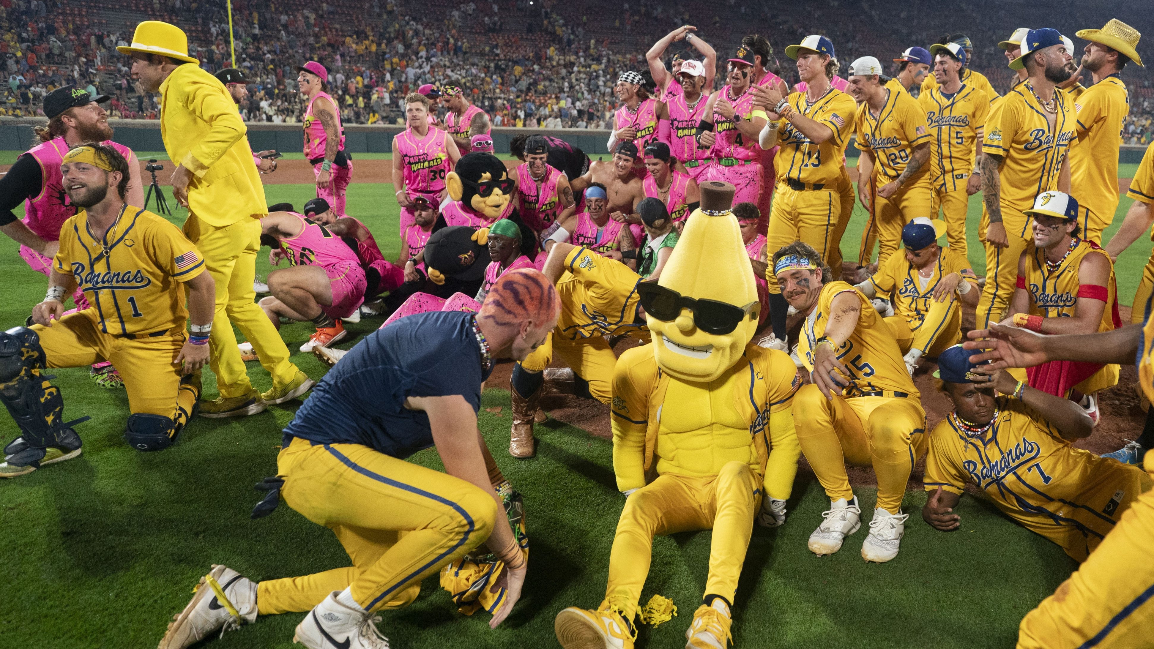 The Savannah Bananas players and Party Animals players get up after making a group photo after a game