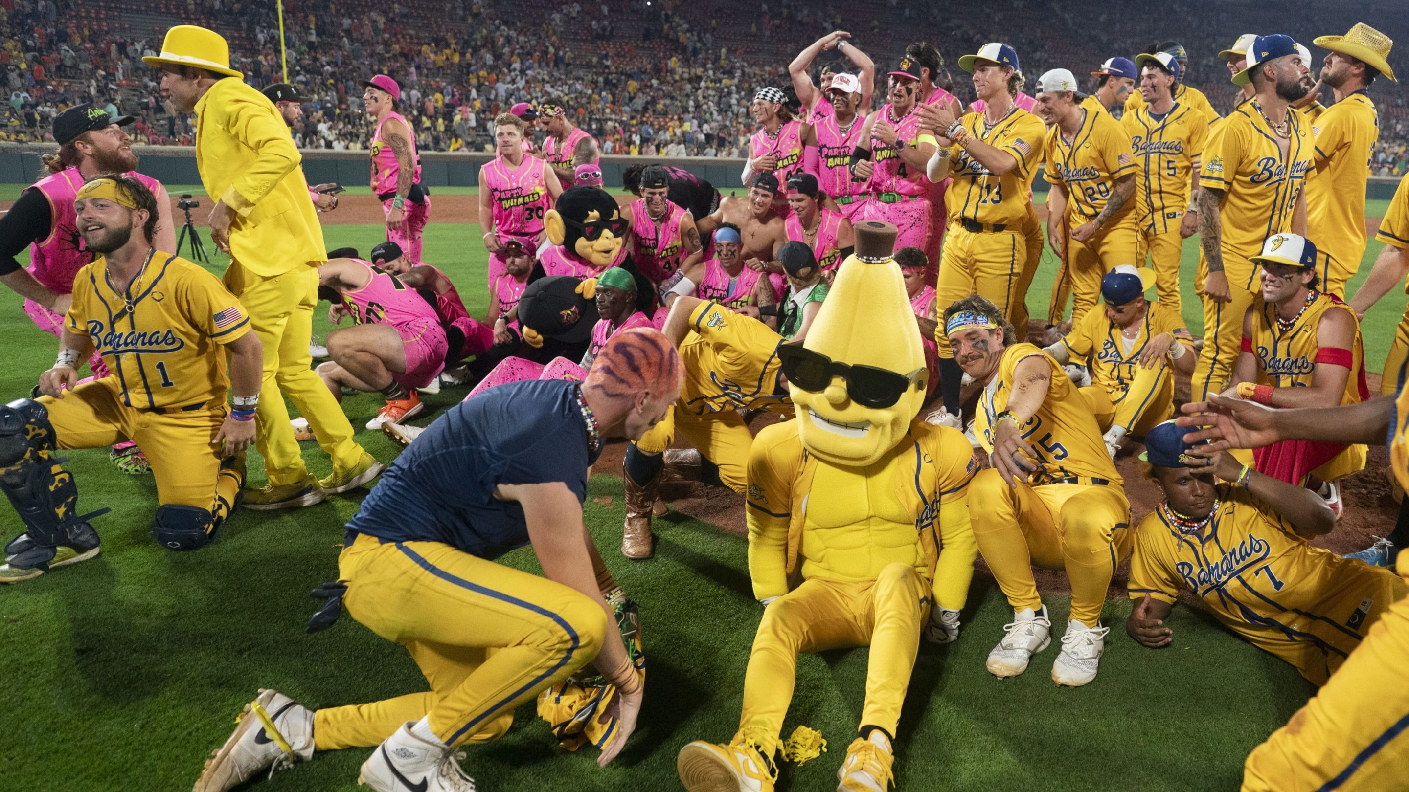 The Savannah Bananas players and Party Animals players get up after making a group photo after a game