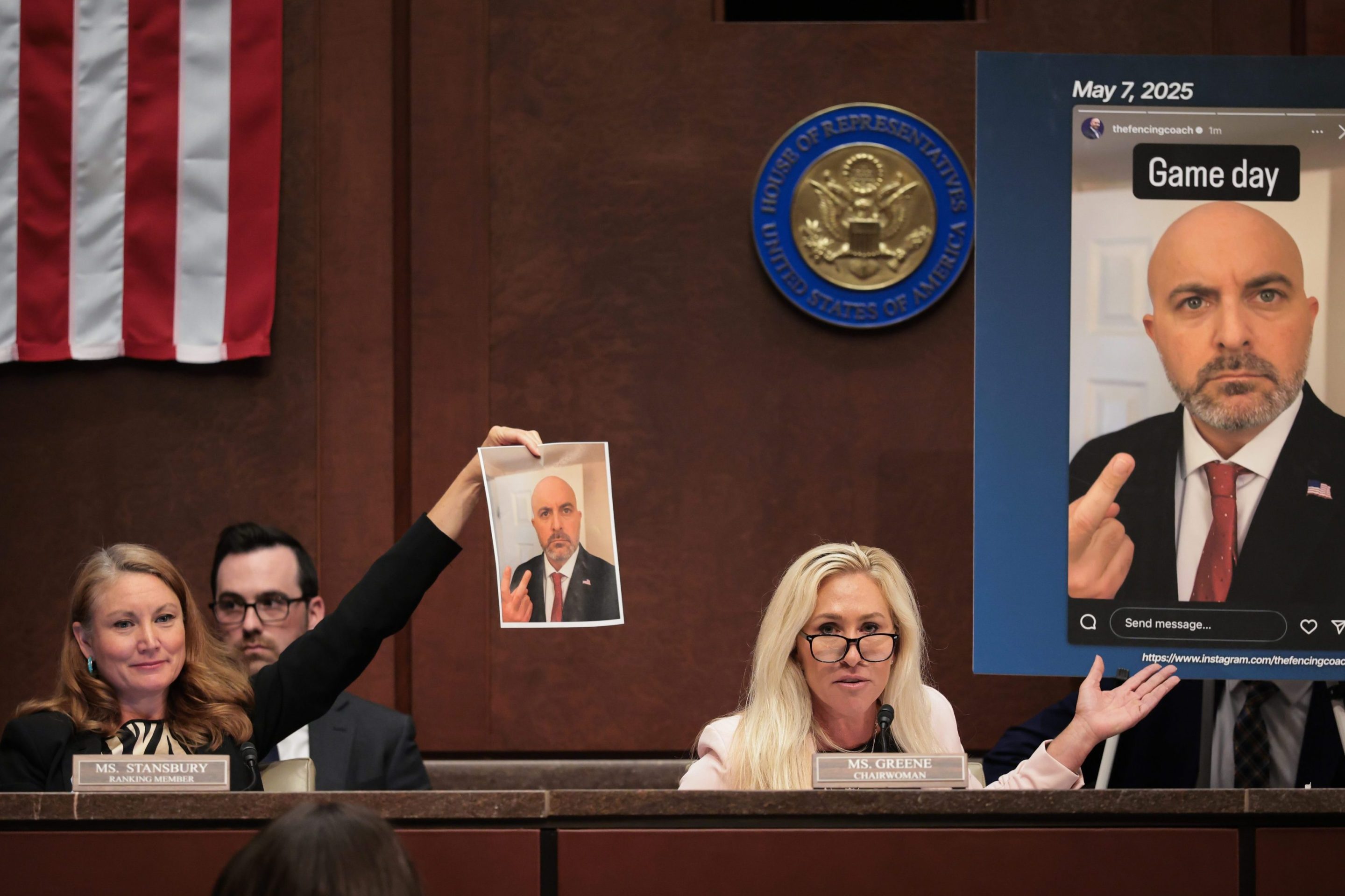 U.S. Rep. Melanie Stansbury (D-NM) (L) and Rep. Marjorie Taylor Greene (R-GA) (R) speak about an alleged screenshot from the Instagram of USA Fencing board director Damien Lehfeldt during the hearing on “Unfair Play: Keeping Men Out of Women’s Sports" held by the Department of Government Efficiency (DOGE) Subcommittee at the U.S. Capitol on May 07, 2025 in Washington, DC. Green is holding a photo that makes it look like Lehfeldt is pointing at himself with his middle finger. Stansbury is holding up a larger capture of the same photo that shows him making a peace sign with the same hand.