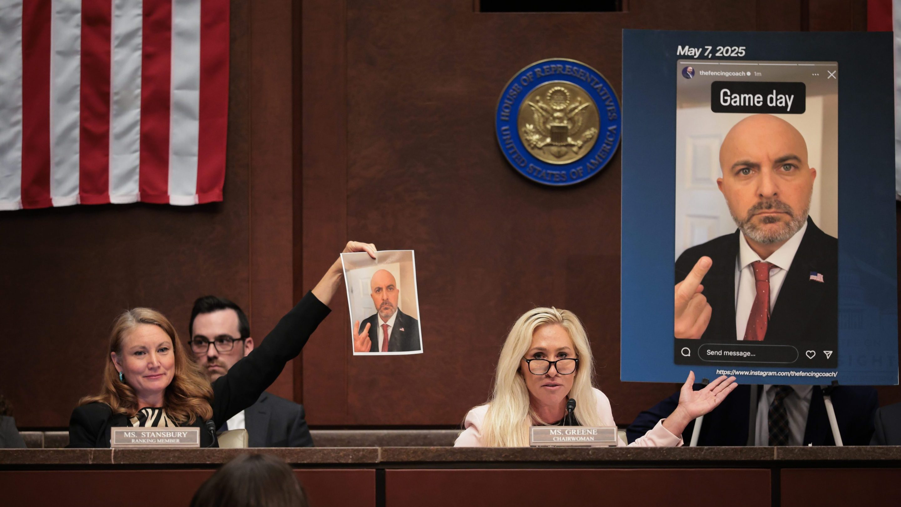 U.S. Rep. Melanie Stansbury (D-NM) (L) and Rep. Marjorie Taylor Greene (R-GA) (R) speak about an alleged screenshot from the Instagram of USA Fencing board director Damien Lehfeldt during the hearing on “Unfair Play: Keeping Men Out of Women’s Sports" held by the Department of Government Efficiency (DOGE) Subcommittee at the U.S. Capitol on May 07, 2025 in Washington, DC. Green is holding a photo that makes it look like Lehfeldt is pointing at himself with his middle finger. Stansbury is holding up a larger capture of the same photo that shows him making a peace sign with the same hand.