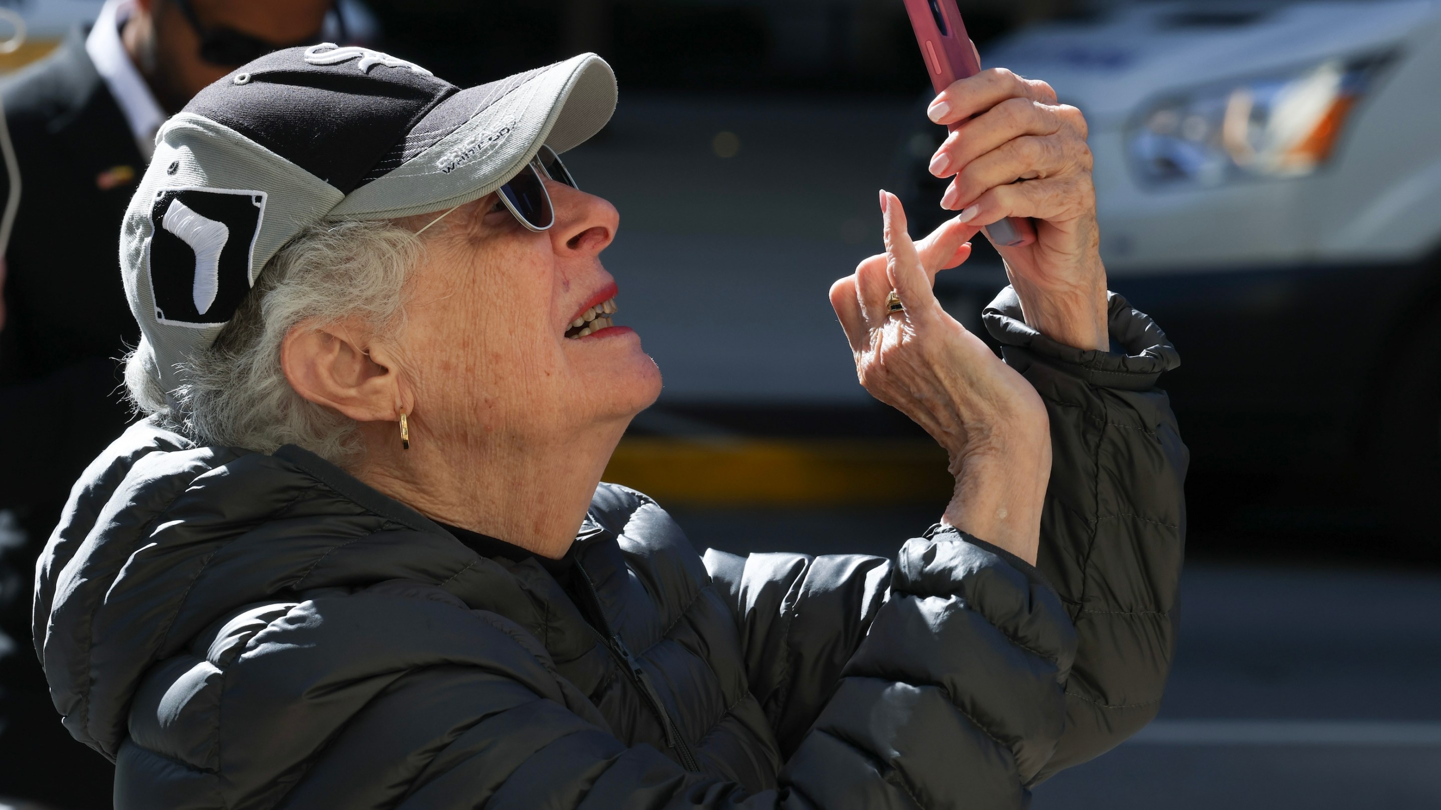 A passer-by looks on as worker hangs papal bunting over the entrance to the Holy Name Cathedral after Cardinal Robert Prevost, who was born in Chicago, had been named as first American leader of the Catholic Church. She's wearing a White Sox hat.