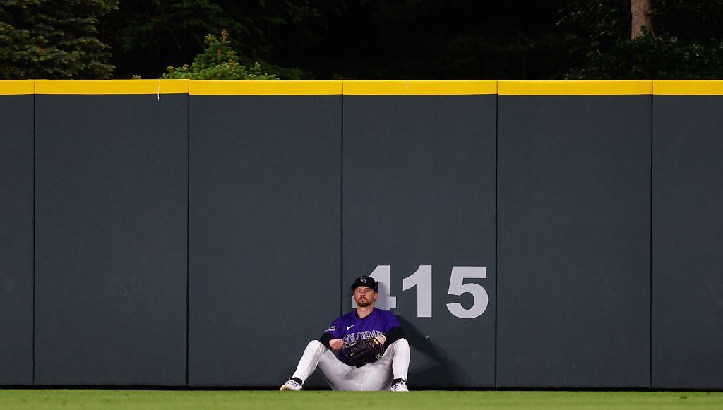 A dejected Brenton Doyle #9 of the Colorado Rockies sits on the ground after a go-ahead two run home run off the bat of Alec Bohm of the Philadelphia Phillies flew over his glove in the eighth inning at Coors Field on May 19, 2025 in Denver, Colorado.