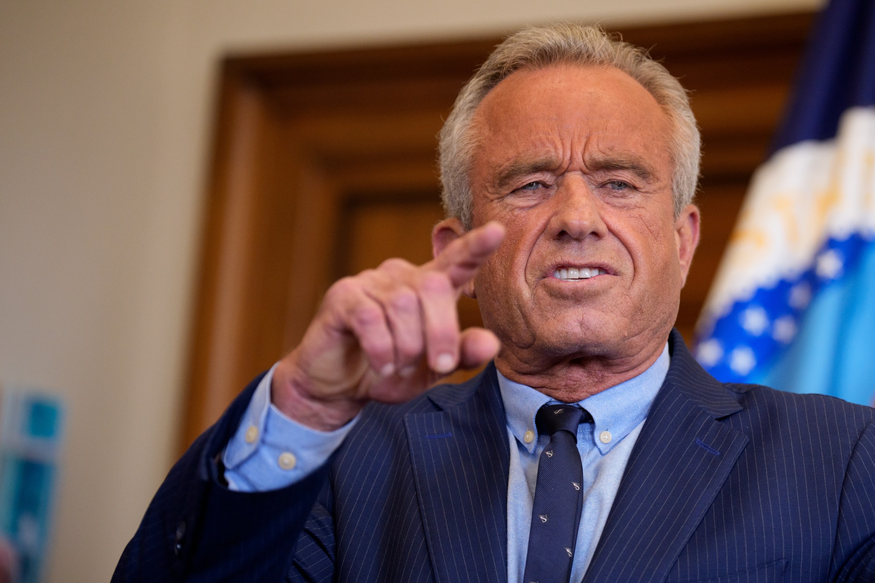 Health and Human Services Secretary Robert F. Kennedy Jr. speaks. He looks like a photographic negative and is grimacing. Skin the color of a hot dog.