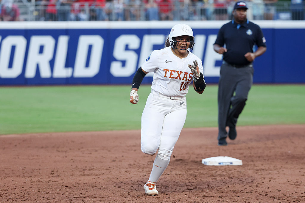 Mia Scott, wearing the all white Texas uniforms, runs between second and third base.