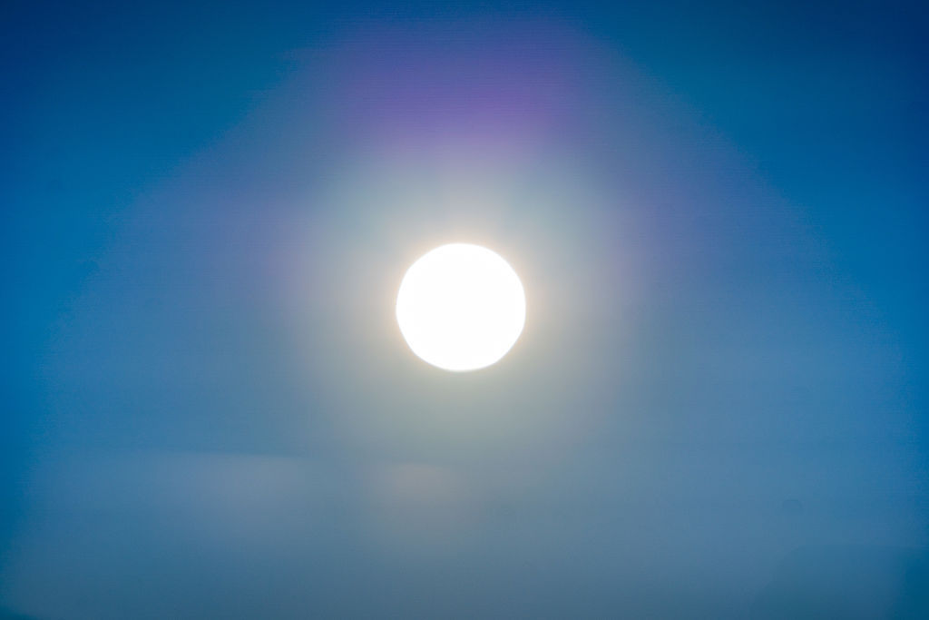 very bright sun in the middle of cloudless blue sky