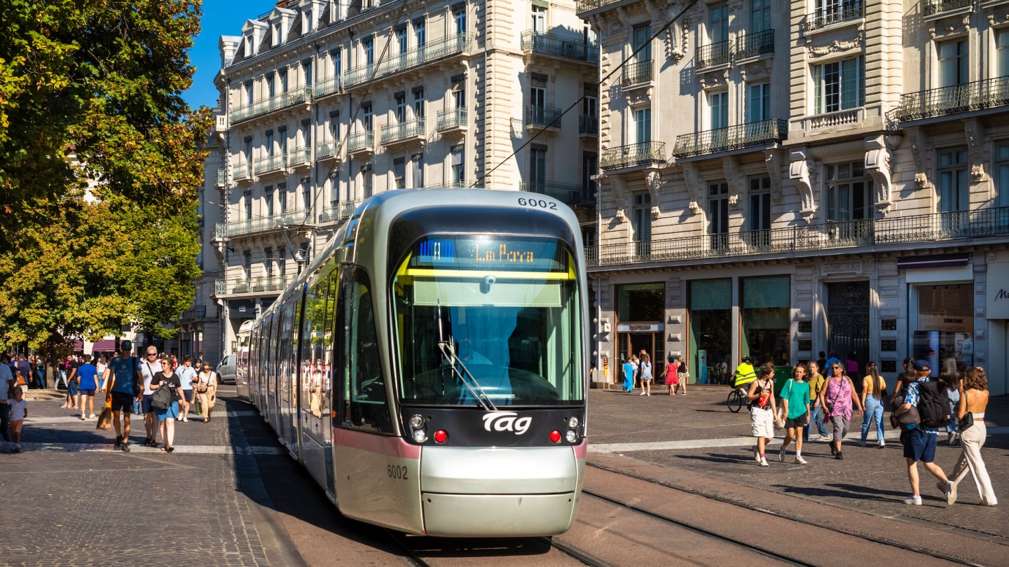 An electric tram moves past peope shopping in Rue Felix Poulat in the centre of Grenoble, France.
