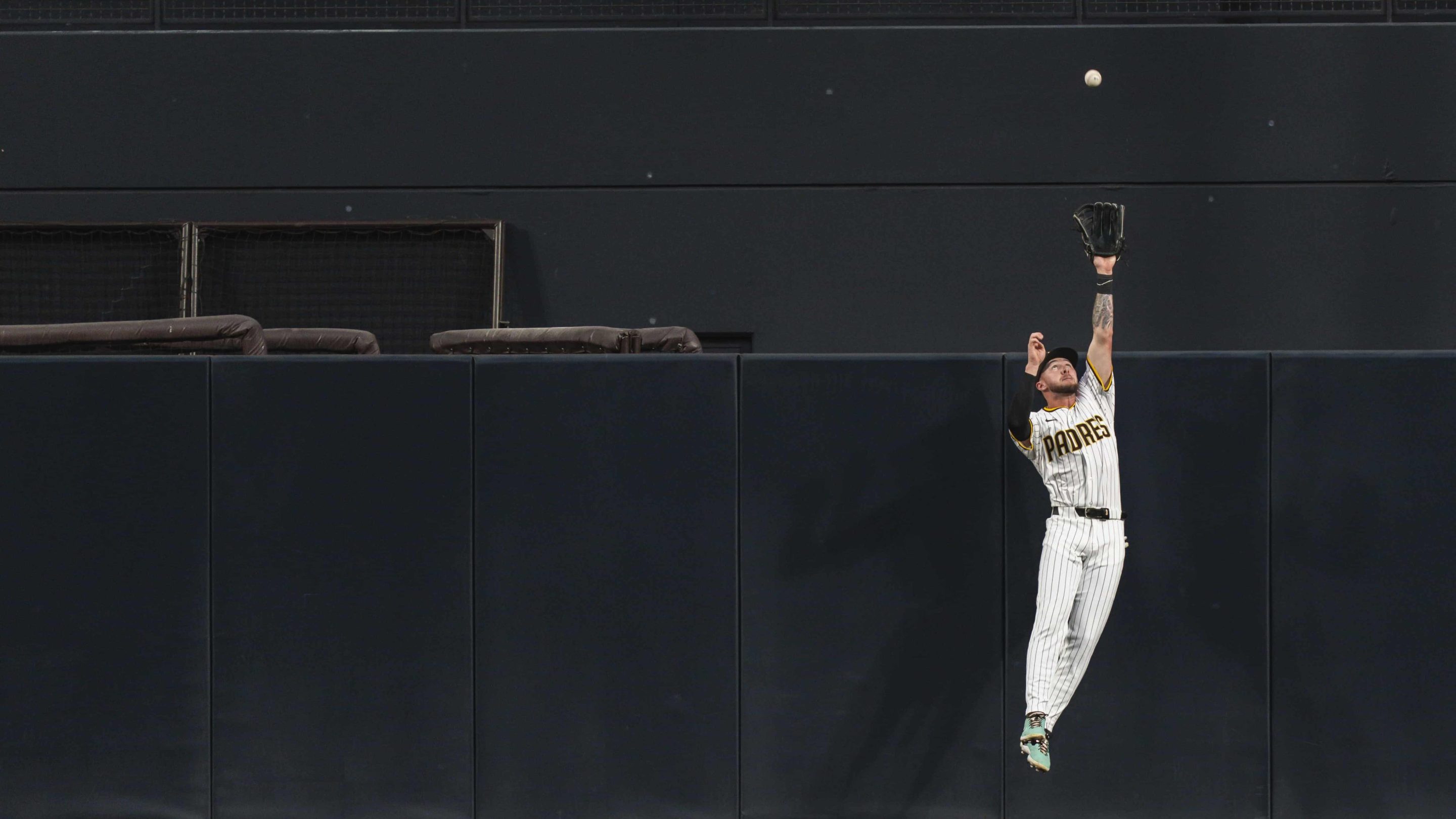 jackson merril leaps up over the outfield fence to grab a ball