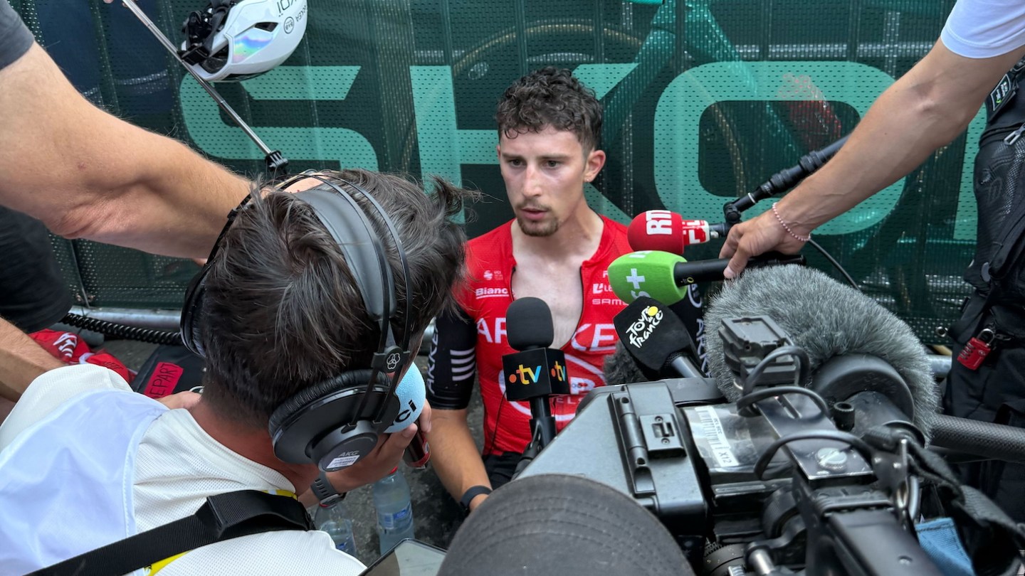 Cyclist Kévin Vaquelin sits in front of a scrum of reporters, cameras, and microphones after Stage 12 of the 2025 Tour de France. He seems pretty beat.