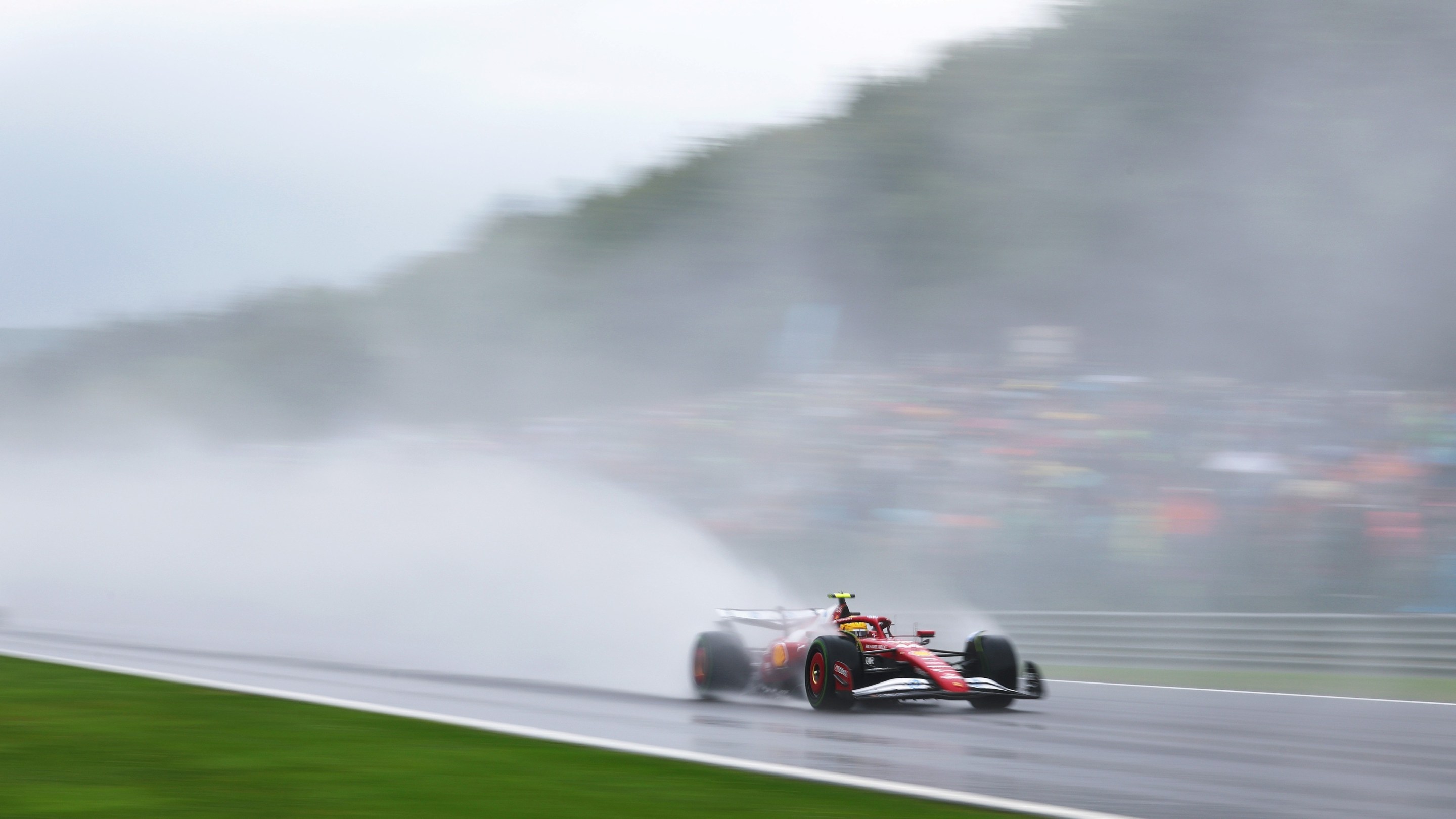 Lewis Hamilton of Great Britain driving the (44) Scuderia Ferrari SF-25 on track, a massive spray of water following his car.