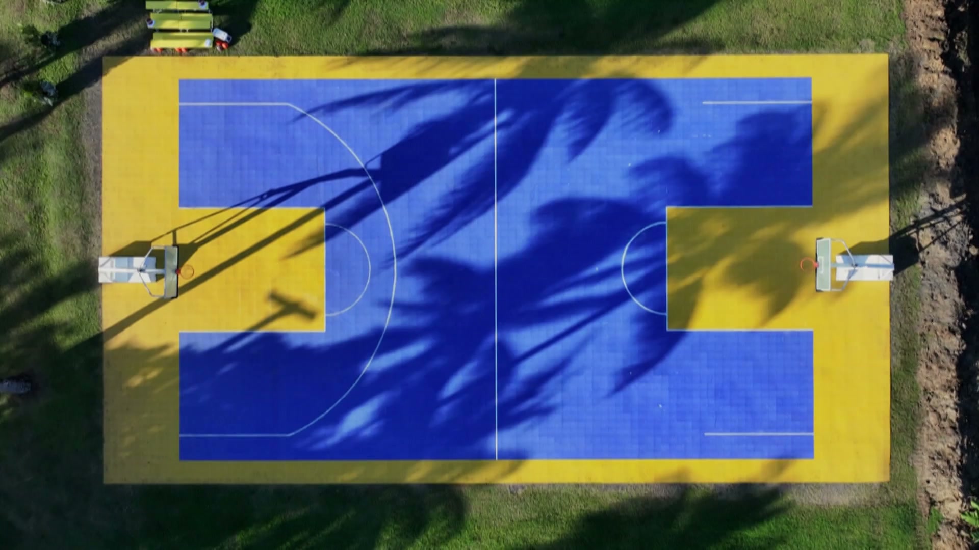 A bird's-eye view of the Love Island basketball court, which resembles a huge blue H on a yellow background. It lacks baselines, and the right half of the court lacks a three-point line. Other than that, it's great