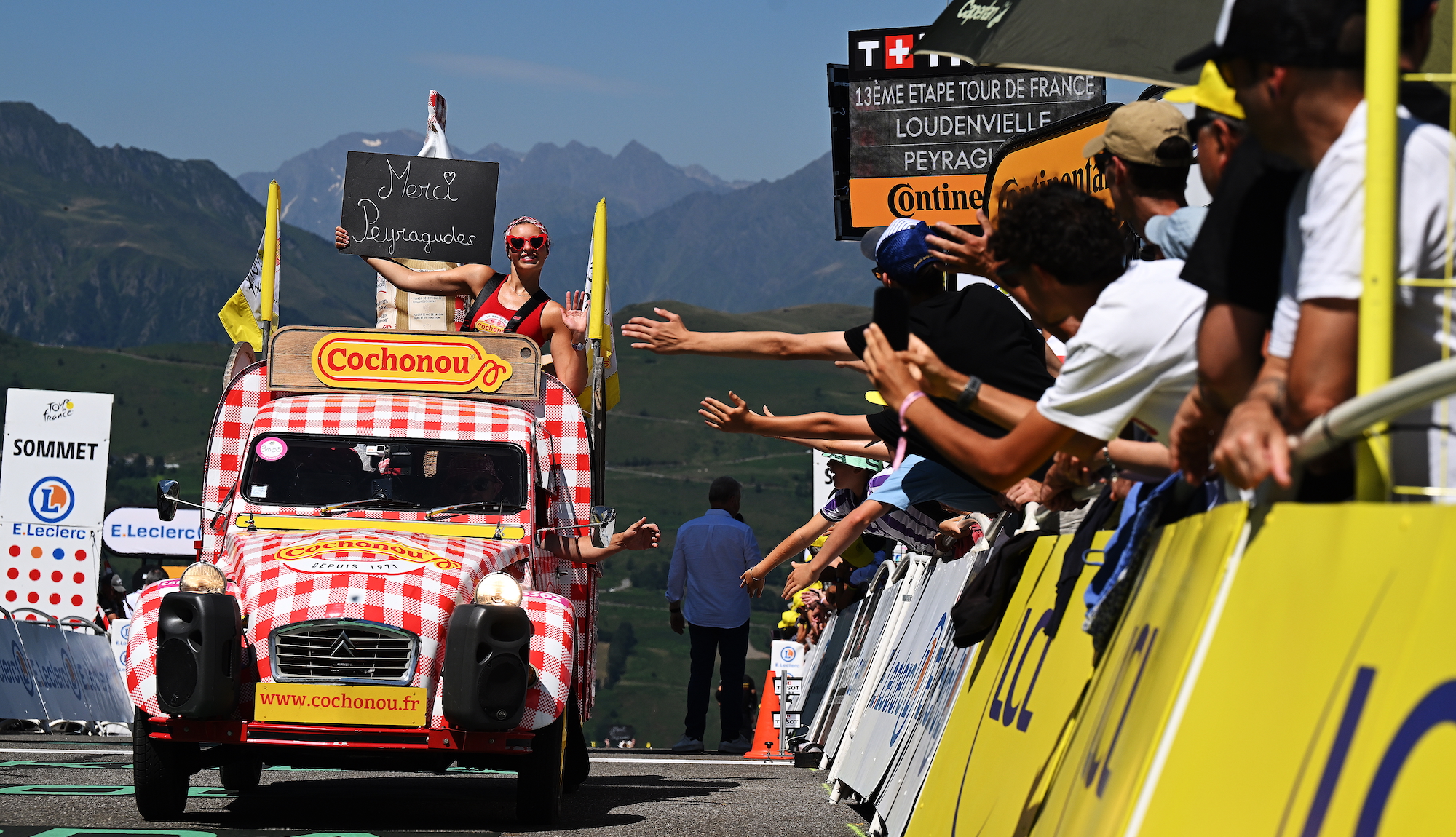 A float for the Cochonou brand in the Tour de France caravan, with spectators reaching out to it as it passes.