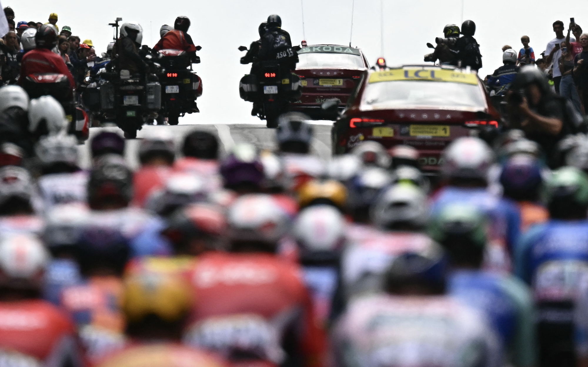 Accredited media motorcycles and race direction vehicles precede the pack of riders (peloton) as they cycle during the 14th stage of the 112th edition of the Tour de France cycling race, 182.6 km between Pau and Luchon-Superbagneres, in the Pyrenees mountains of southwestern France, on July 19, 2025.