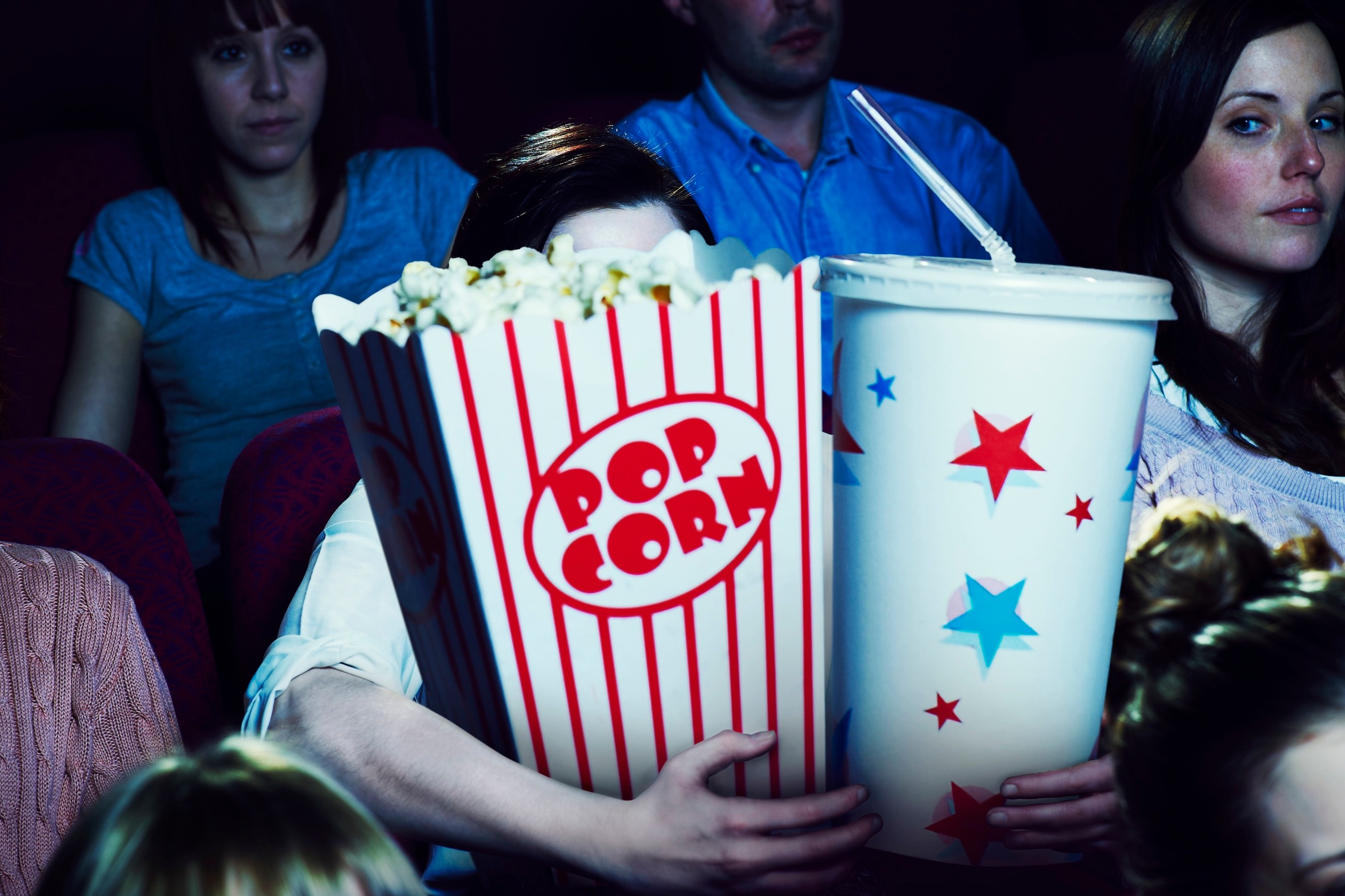 Woman holding giant sized popcorn and drink