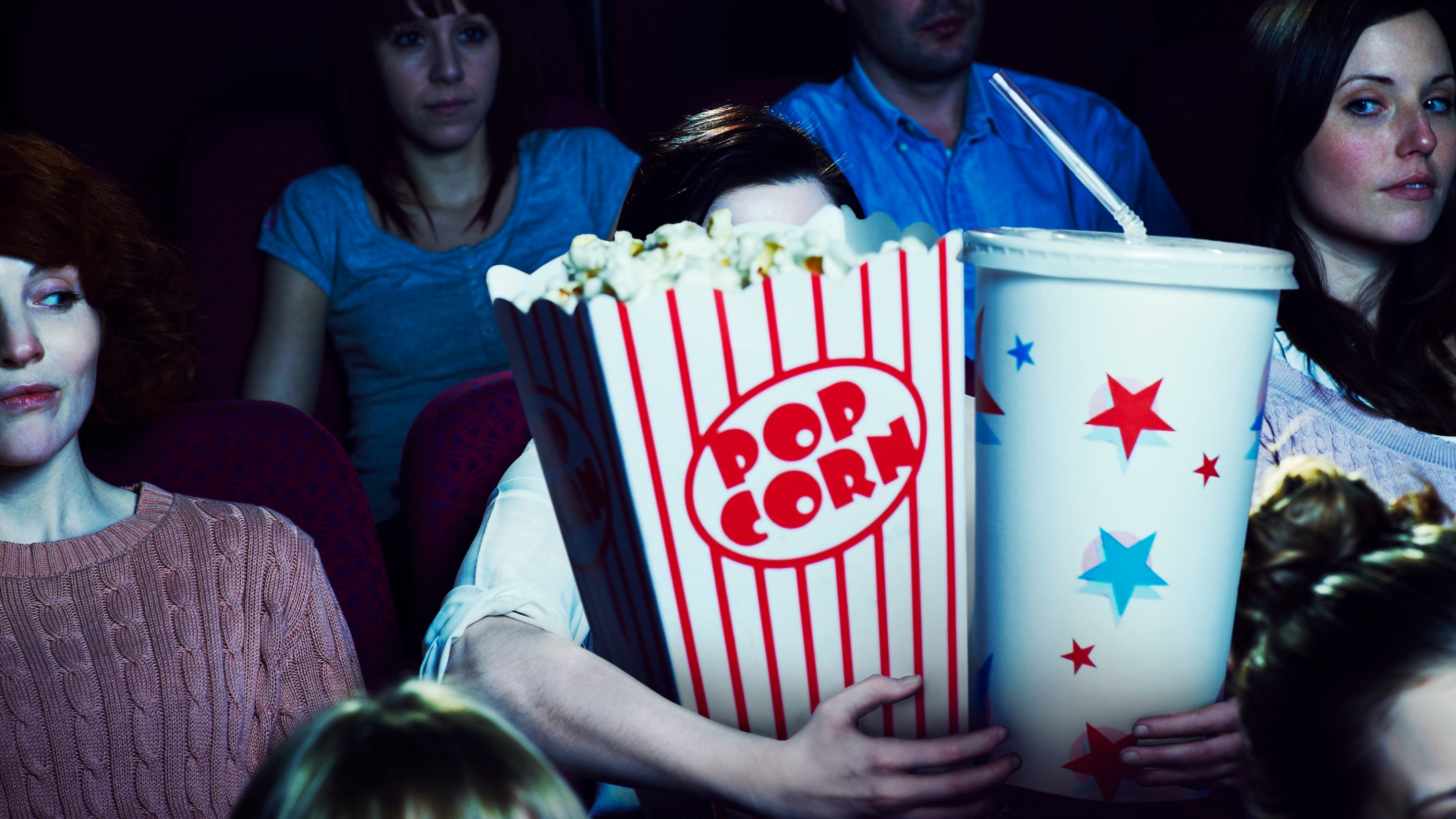 Woman holding giant sized popcorn and drink