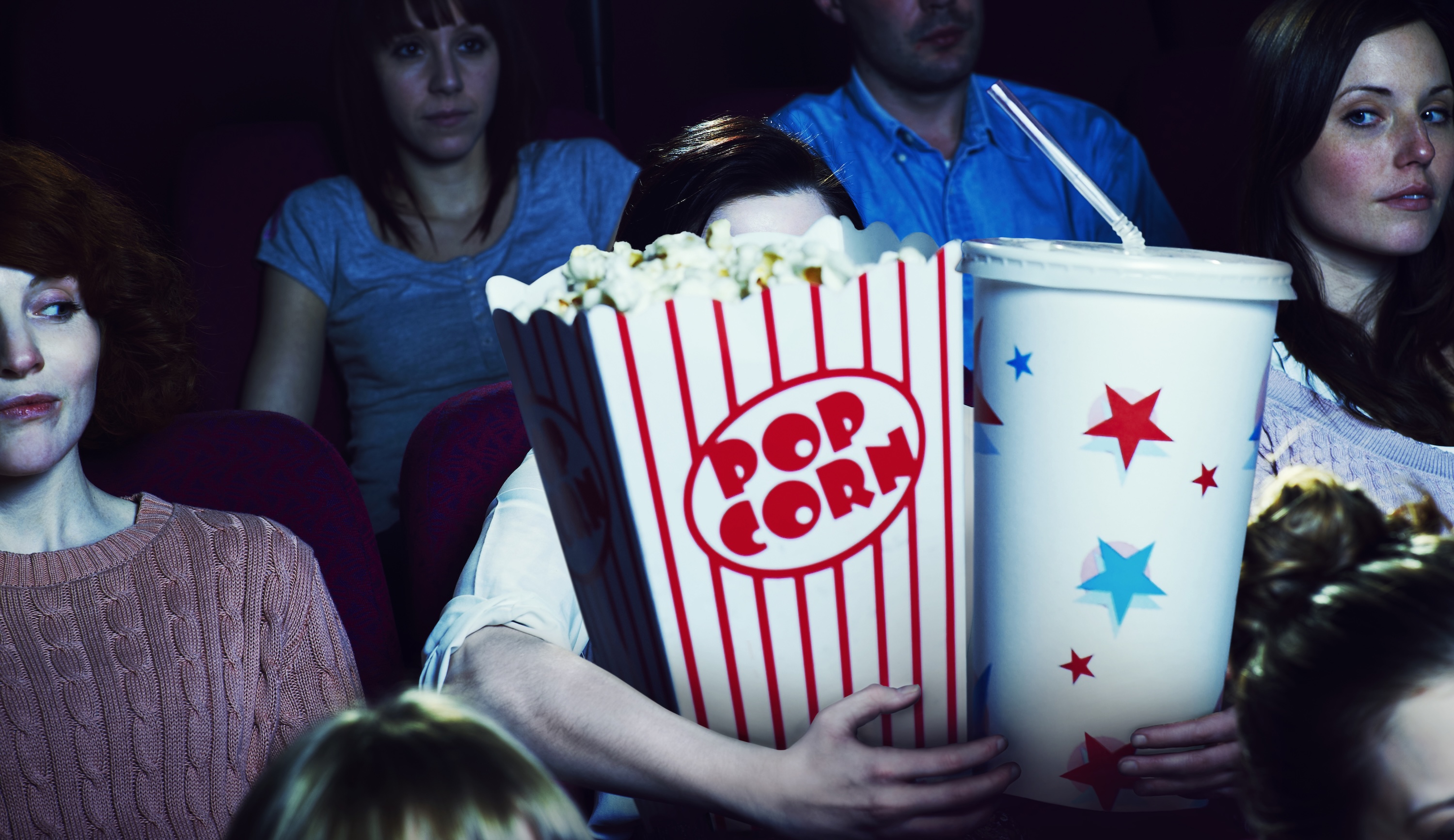 Woman holding giant sized popcorn and drink