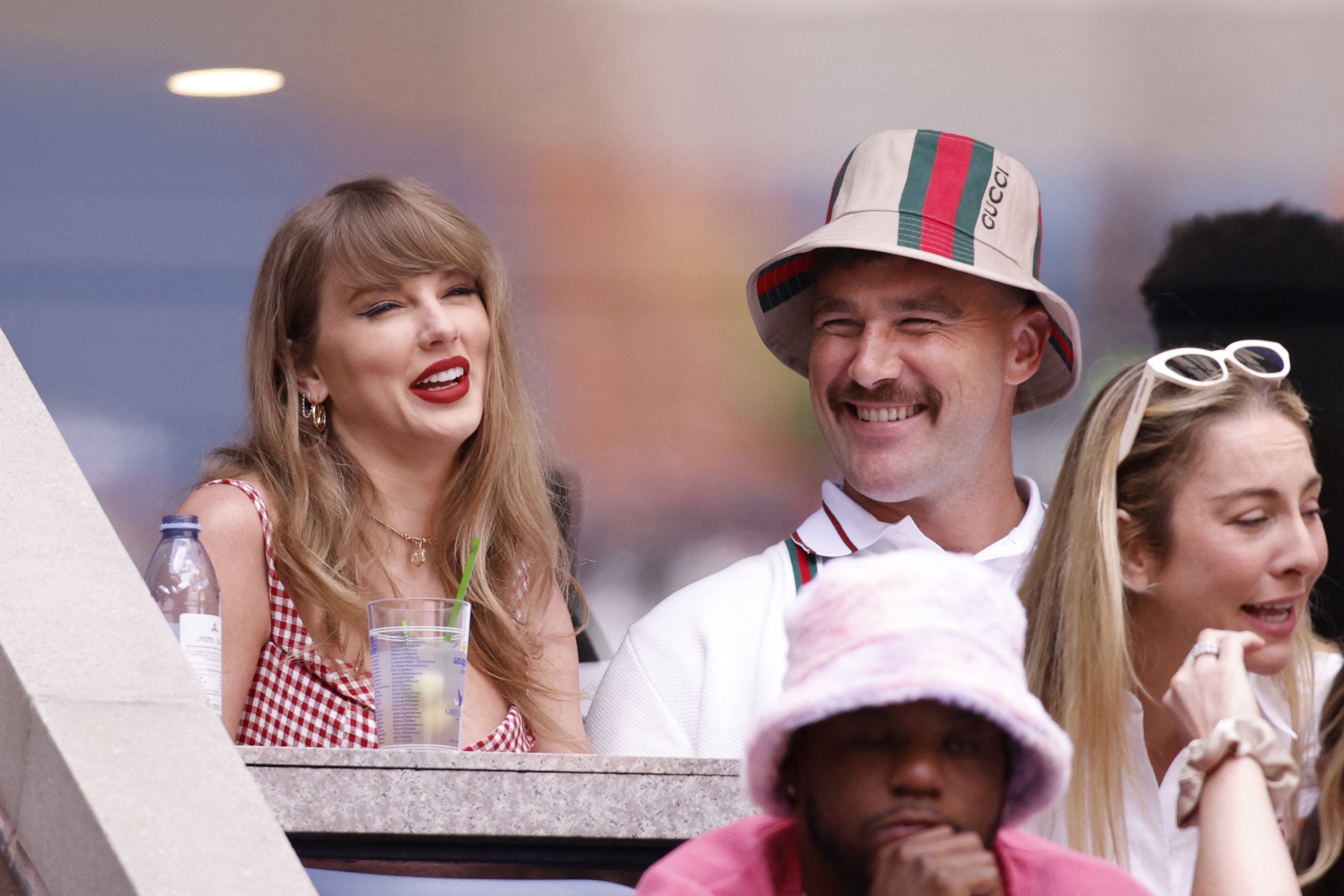 taylor swift and travis kelce at the 2024 US. Open. He is wearing a stupid hat and looking at her lovingly.