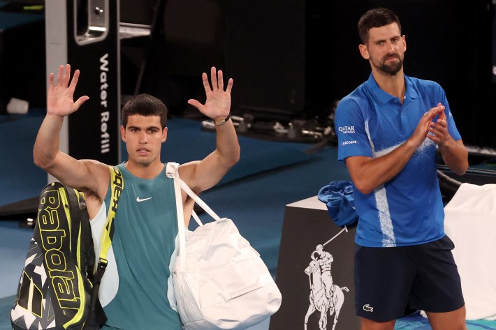 Spain's Carlos Alcaraz (L) acknowledges the spectators as he walks off the court after his defeat to Serbia's Novak Djokovic (R) in the men's singles quarterfinal match on day ten of the Australian Open tennis tournament in Melbourne on January 22, 2025.