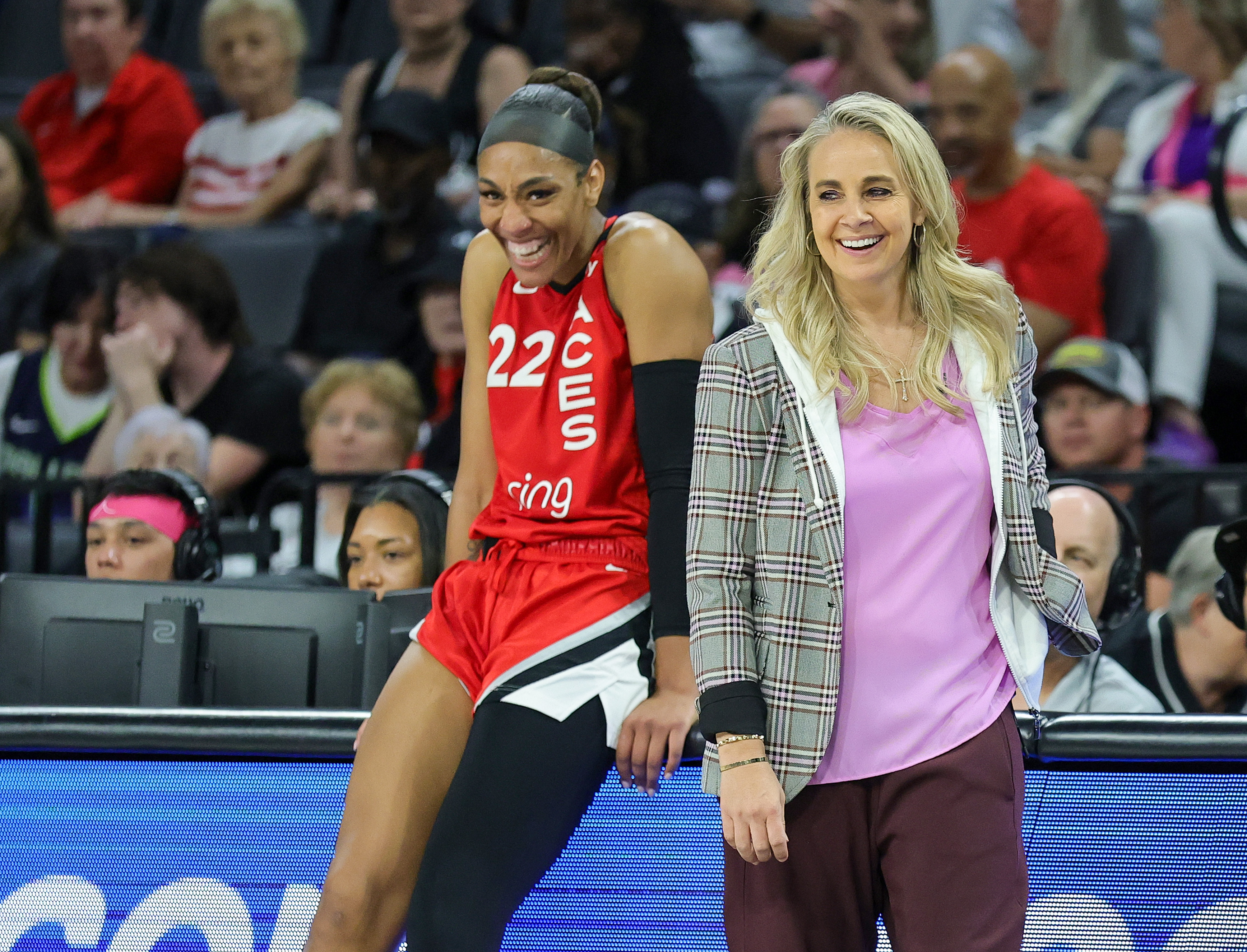 A'ja Wilson #22 and head coach Becky Hammon of the Las Vegas Aces laugh as Wilson waits to check in during the fourth quarter of a game against the Dallas Wings at Michelob ULTRA Arena on August 17, 2025 in Las Vegas, Nevada. The Aces defeated the Wings 106-87.