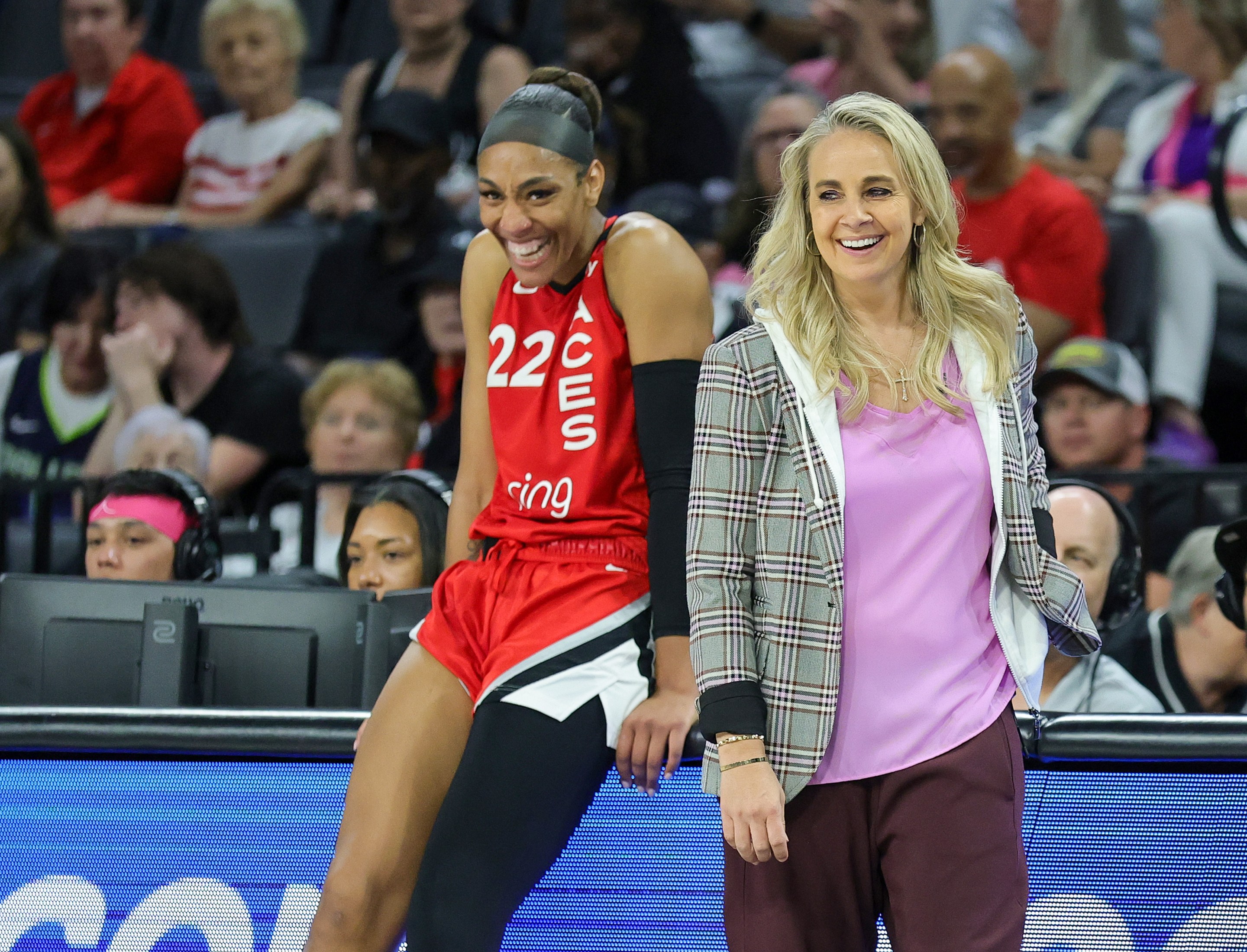 A'ja Wilson #22 and head coach Becky Hammon of the Las Vegas Aces laugh as Wilson waits to check in during the fourth quarter of a game against the Dallas Wings at Michelob ULTRA Arena on August 17, 2025 in Las Vegas, Nevada. The Aces defeated the Wings 106-87.