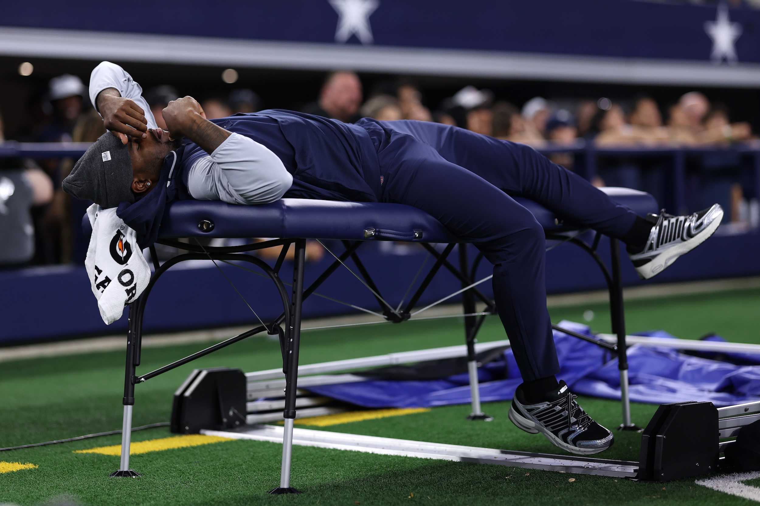 Micah Parsons lying down on a table on the sidelines.