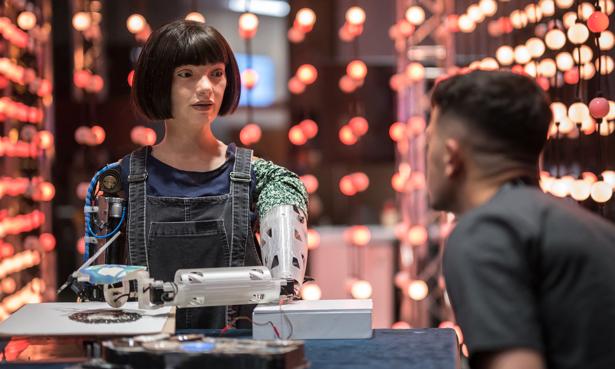 A man faces the realistic artist" robot "Ai-Da" using artificial intelligence at a stand during the International Telecommunication Union (ITU) AI for Good Global Summit in Geneva on May 30, 2024.