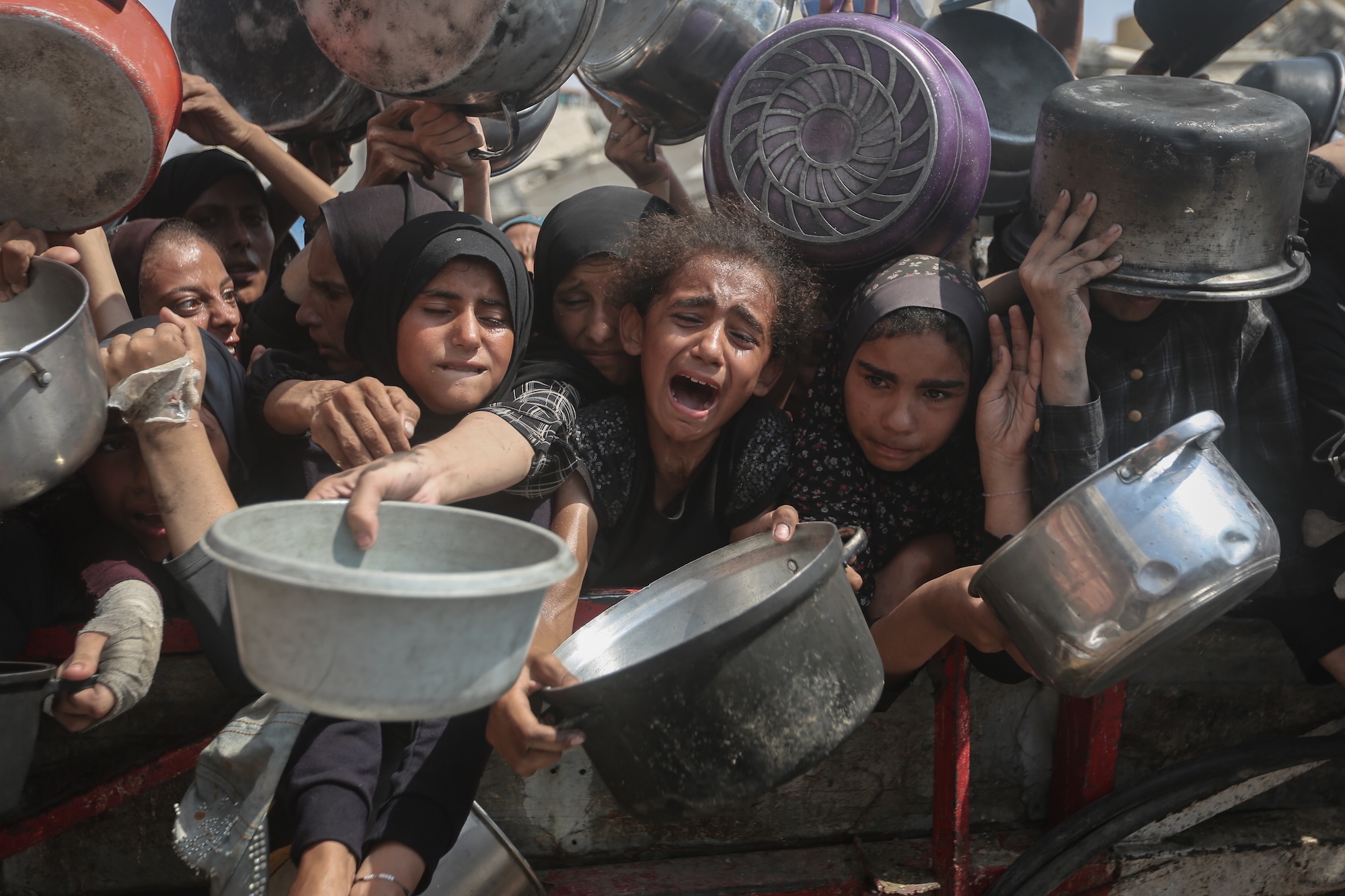 Starving Palestinians including women and children holding pots wait to receive food distributed by a charity organization as Israel continue to block humanitarian aid from reaching the Gaza Strip on August 10, 2025.