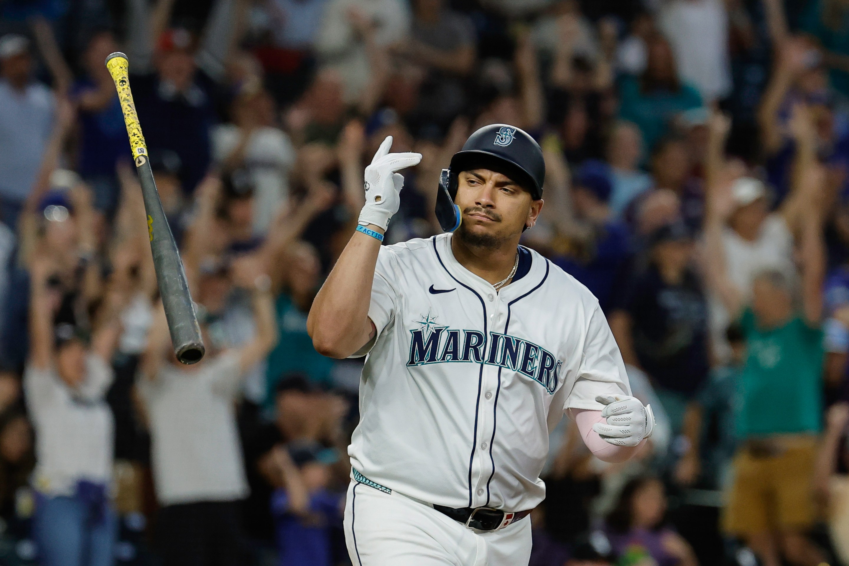 Josh Naylor #12 of the Seattle Mariners flips his bat after hitting a two-run home run.