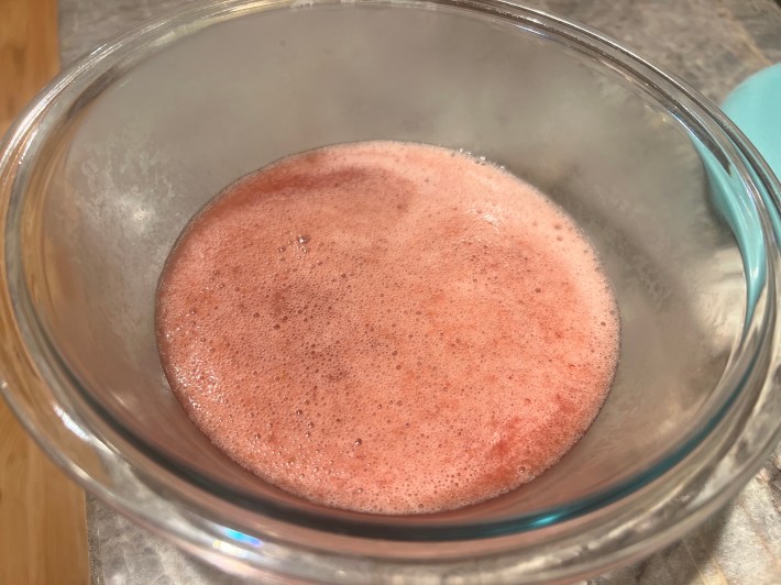 A glass bowl with processed, slightly foamy, still-warm strawberry jam.