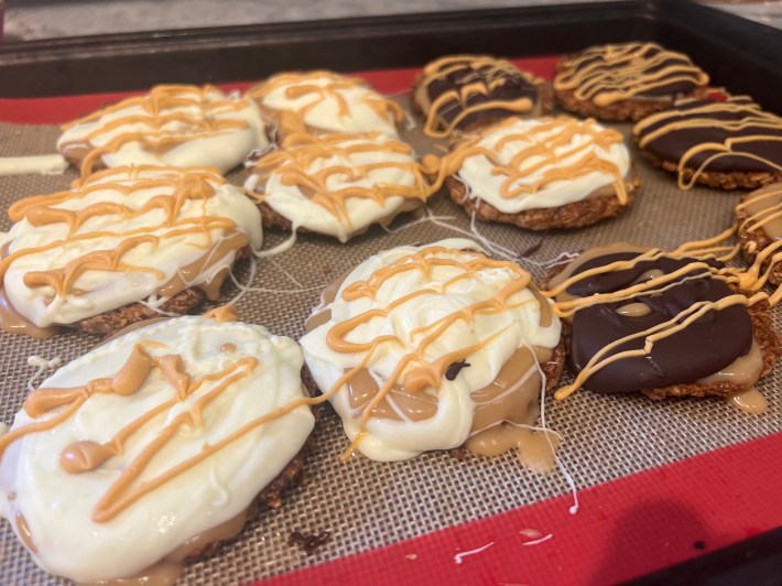 Twelve finished cookies, some coated in white chocolate, others in dark chocolate, with stripes of butterscotch