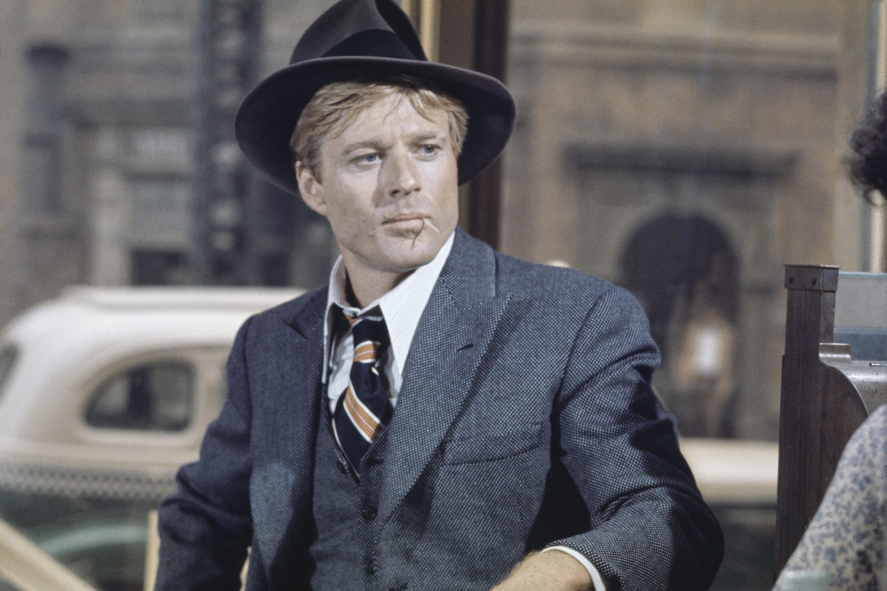 American actor Robert Redford wearing a grey tweed blazer over a matching waistcoat and a white shirt, with a diagonally striped tie, with a grey fedora, in a scene from 'The Sting', filmed in the United States, 1973.