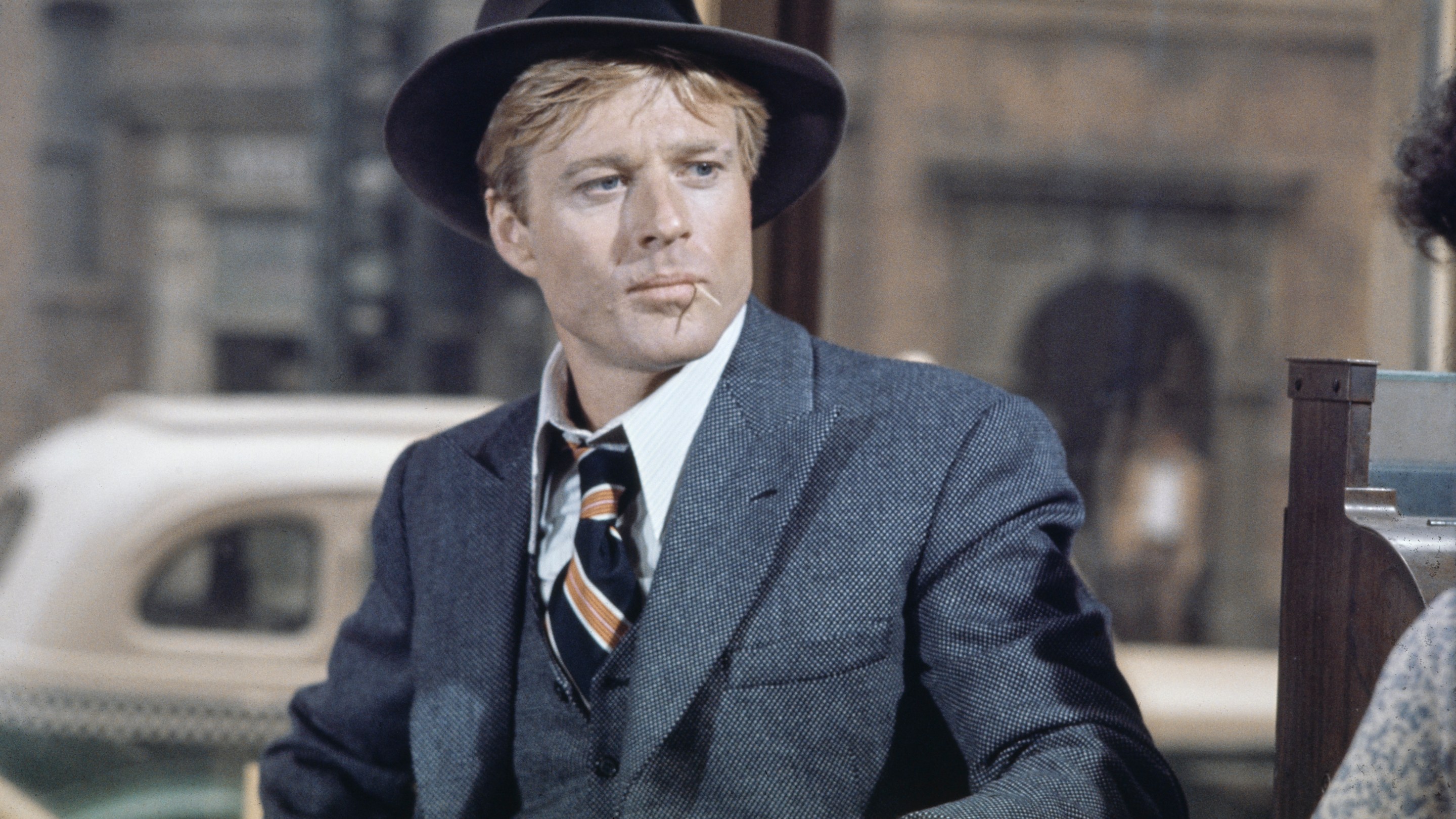 American actor Robert Redford wearing a grey tweed blazer over a matching waistcoat and a white shirt, with a diagonally striped tie, with a grey fedora, in a scene from 'The Sting', filmed in the United States, 1973.