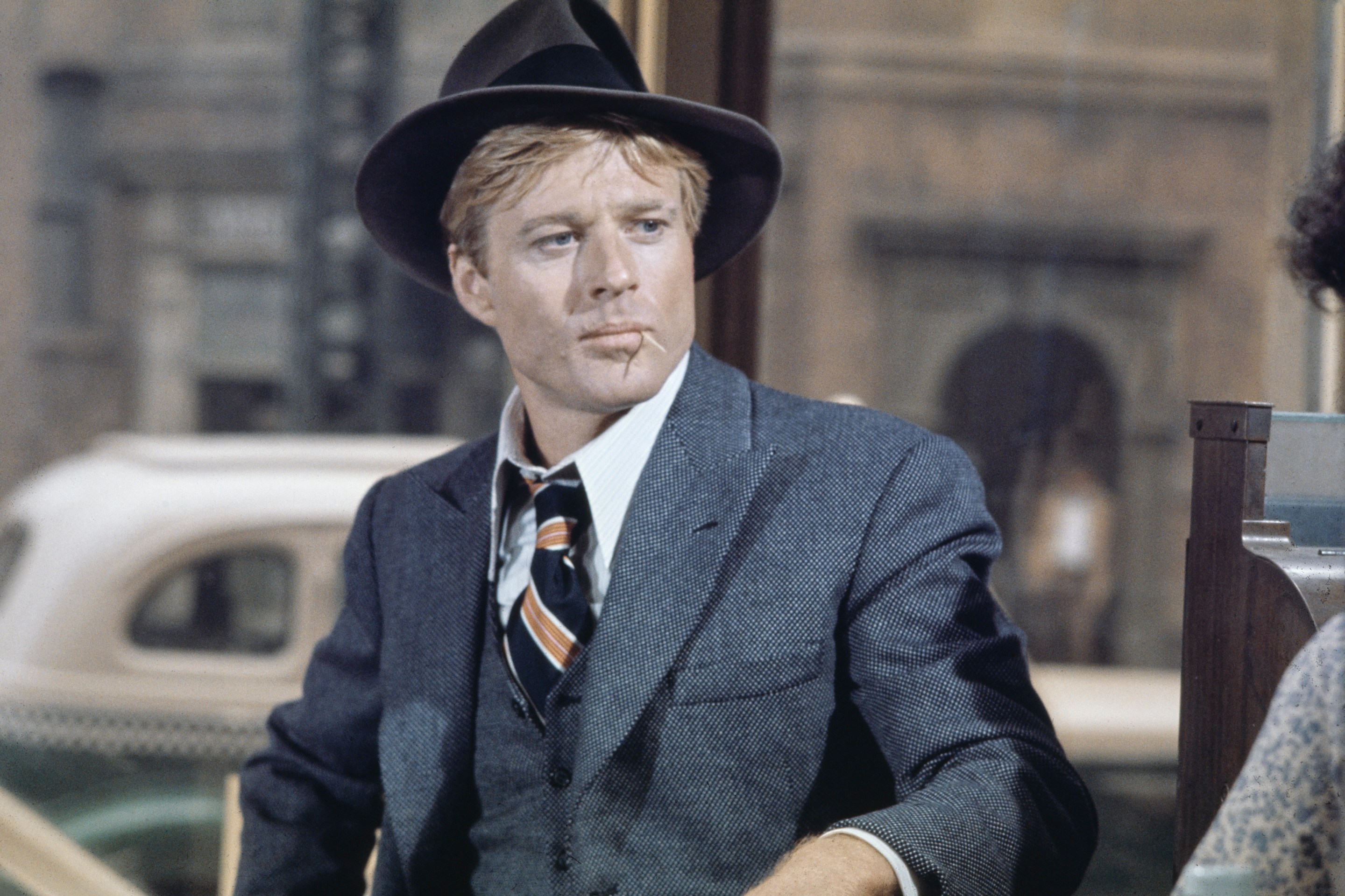 American actor Robert Redford wearing a grey tweed blazer over a matching waistcoat and a white shirt, with a diagonally striped tie, with a grey fedora, in a scene from 'The Sting', filmed in the United States, 1973.