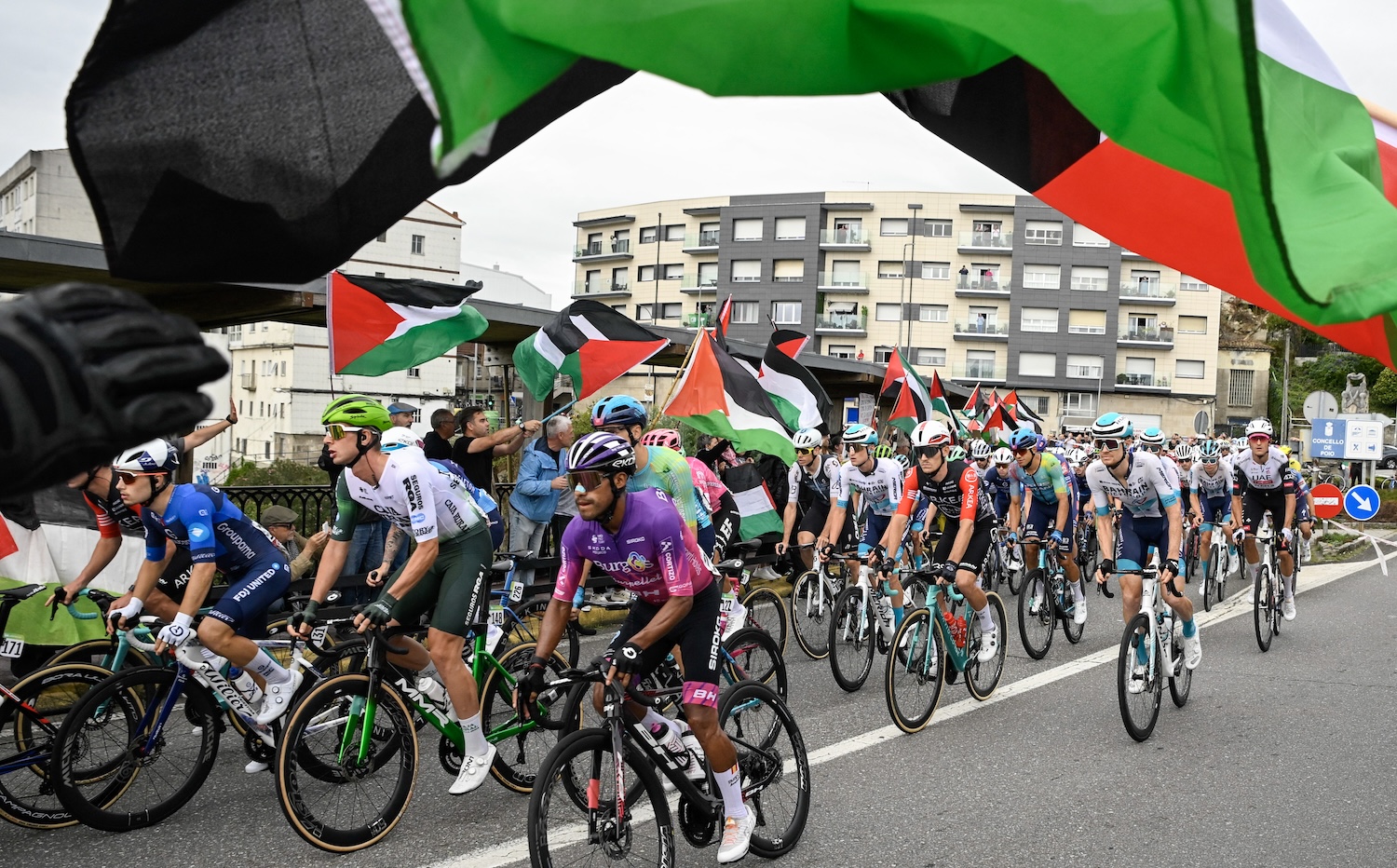 Pro-Palestinian protesters wave flags and shout as the peloton rides by in Poio at the start of the 16th stage of the Vuelta a Espana, a 172 km race between Poio and Castro de Herville, on September 9, 2025. (Photo by Miguel RIOPA / AFP)
