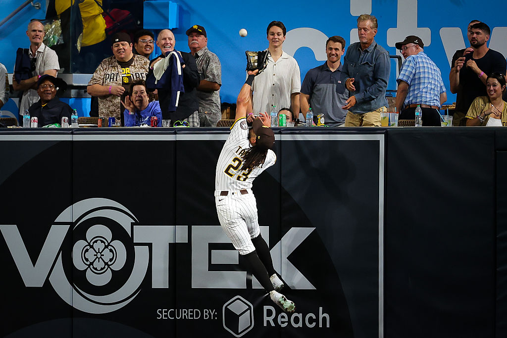 Fernando Tatis Jr. extends up over the right field wall to steal a home run.