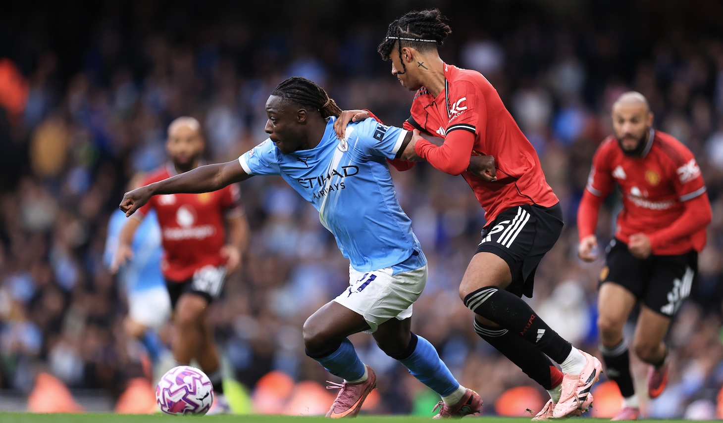 Jeremy Doku of Manchester City holds off the challenge of Leny Yoro of Manchester United during the Premier League match between Manchester City and Manchester United at Etihad Stadium on September 14, 2025 in Manchester, England.