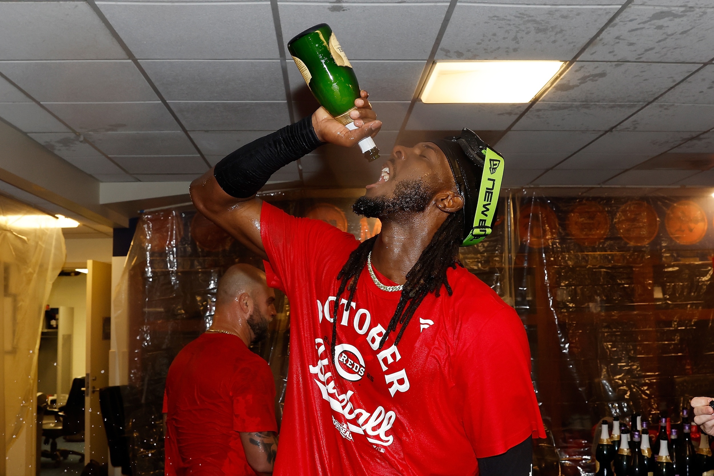 Elly De La Cruz attempts to drink from an empty champagne bottle.