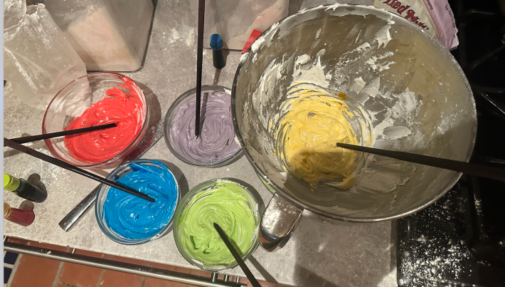 Bowls of colored icing with chopsticks for mixing