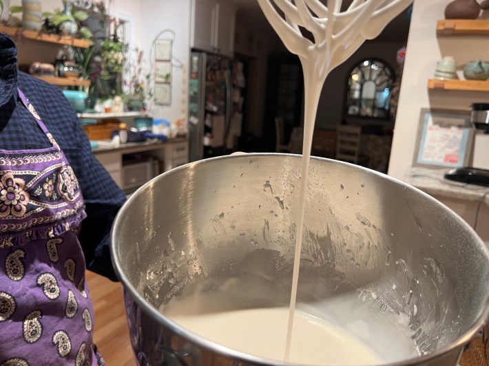 Vanilla glaze dripping off a whisk.