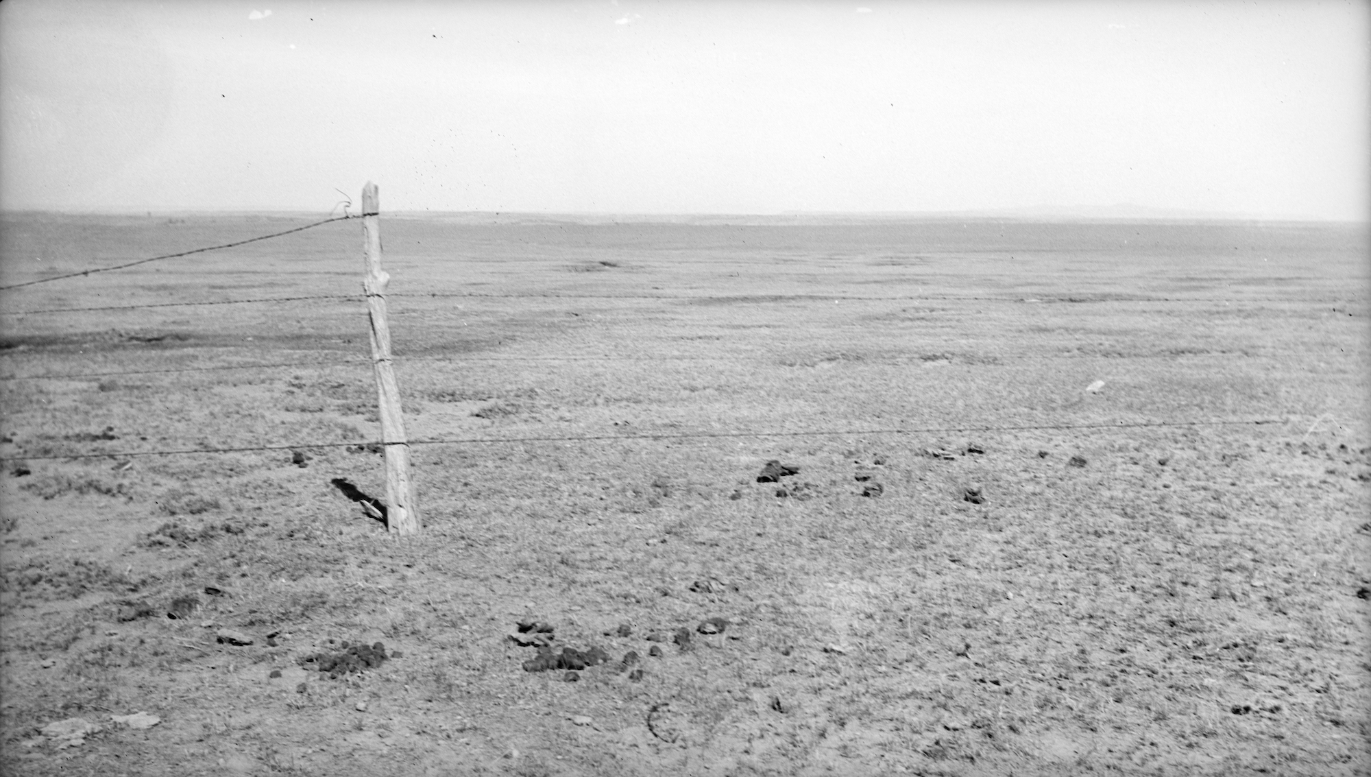 A barren Dust Bowl wasteland with a single fencepost standing in the foreground.
