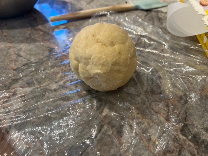 A ball of dough sits on plastic film.