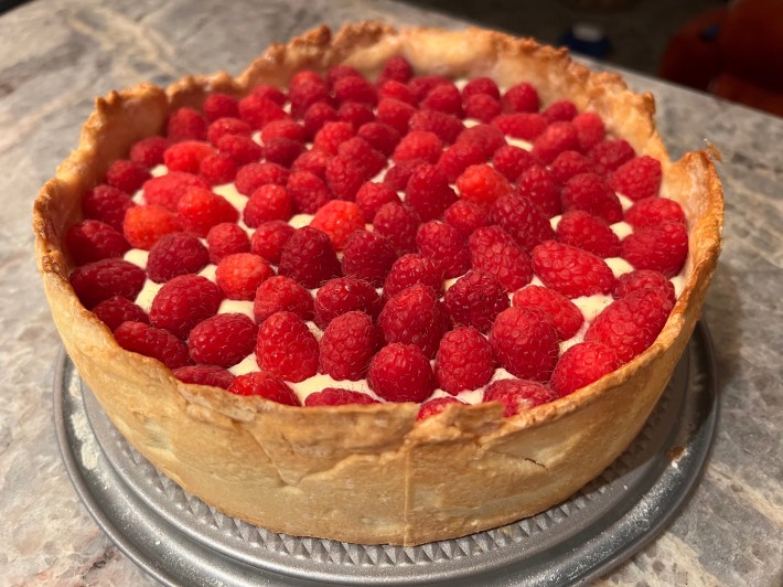 Raspberries arranged on top of liquid curd, inside a tart crust.