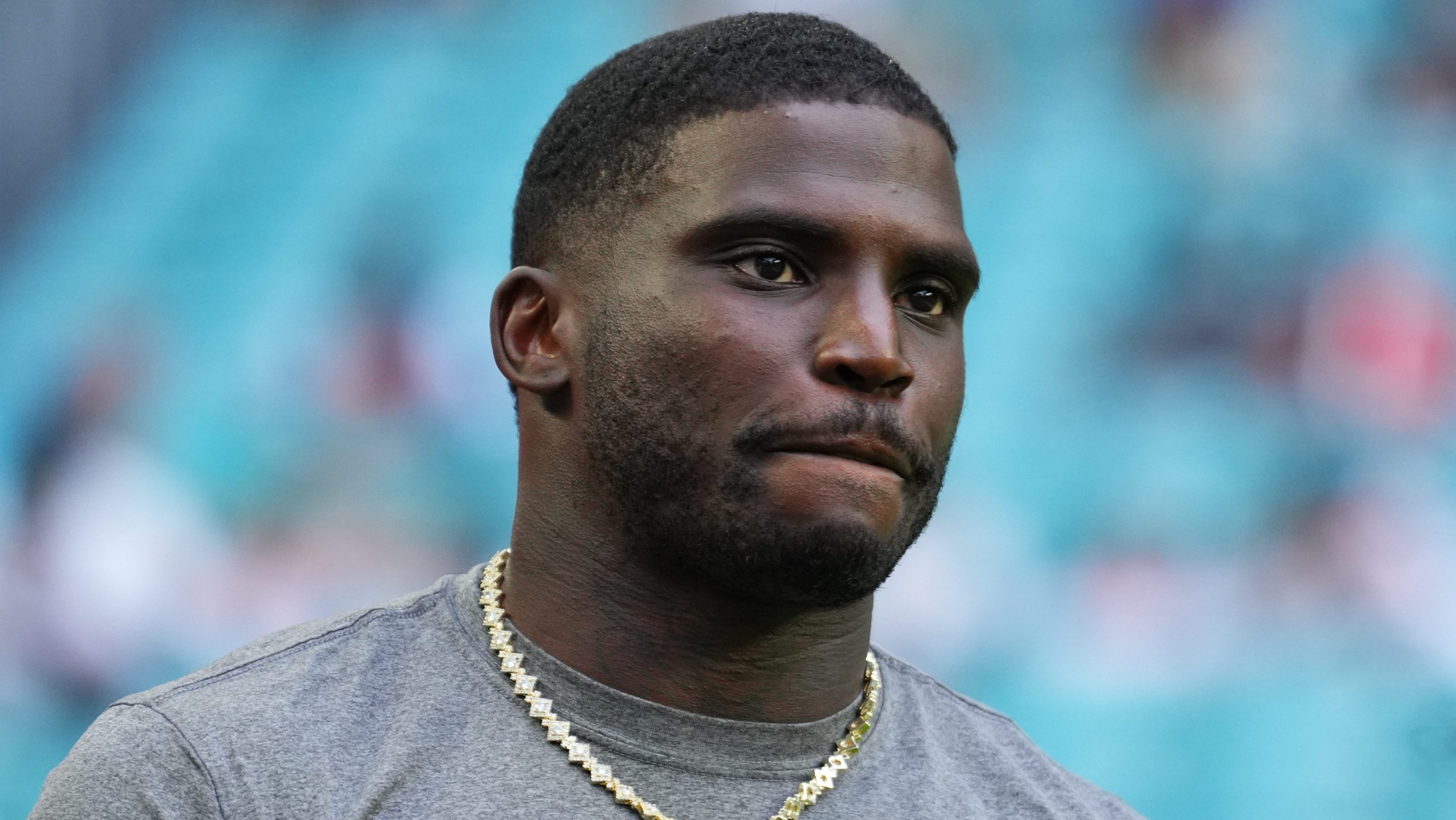 Tyreek Hill #10 of the Miami Dolphins looks on prior to a NFL Preseason 2025 game between Jacksonville Jaguars and Miami Dolphins at Hard Rock Stadium on August 23, 2025 in Miami Gardens, Florida. He is wearing a grey shirt with the Dolphins logo.