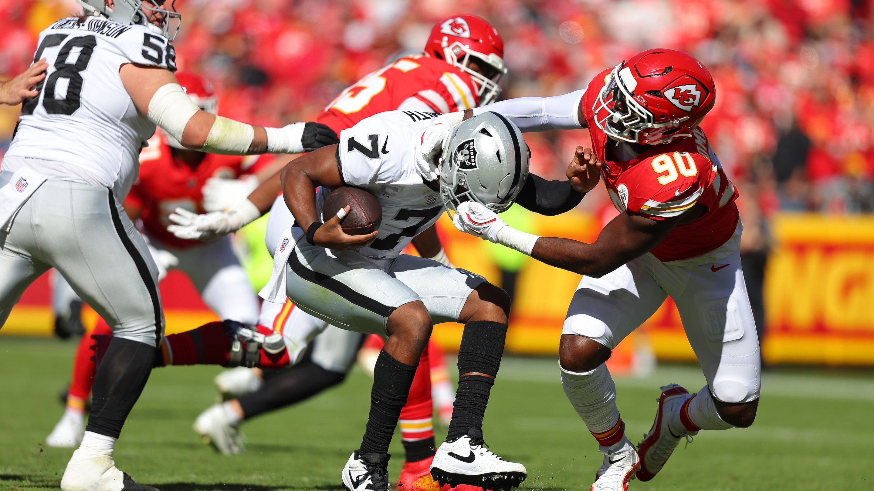 Charles Omenihu #90 of the Kansas City Chiefs grabs the face mask of Geno Smith #7 of the Las Vegas Raiders during the first quarter in the game at Arrowhead Stadium on October 19, 2025 in Kansas City, Missouri.