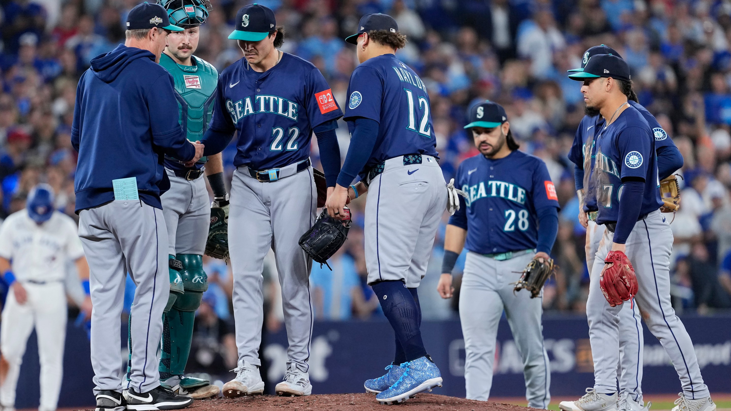 TORONTO, ONTARIO - OCTOBER 20: Manager Dan Wilson #6 of the Seattle Mariners takes the ball from Bryan Woo #22 during a pitching change in the seventh inning against the Toronto Blue Jays in game seven of the American League Championship Series at the Rogers Centre on October 20, 2025 in Toronto, Ontario.