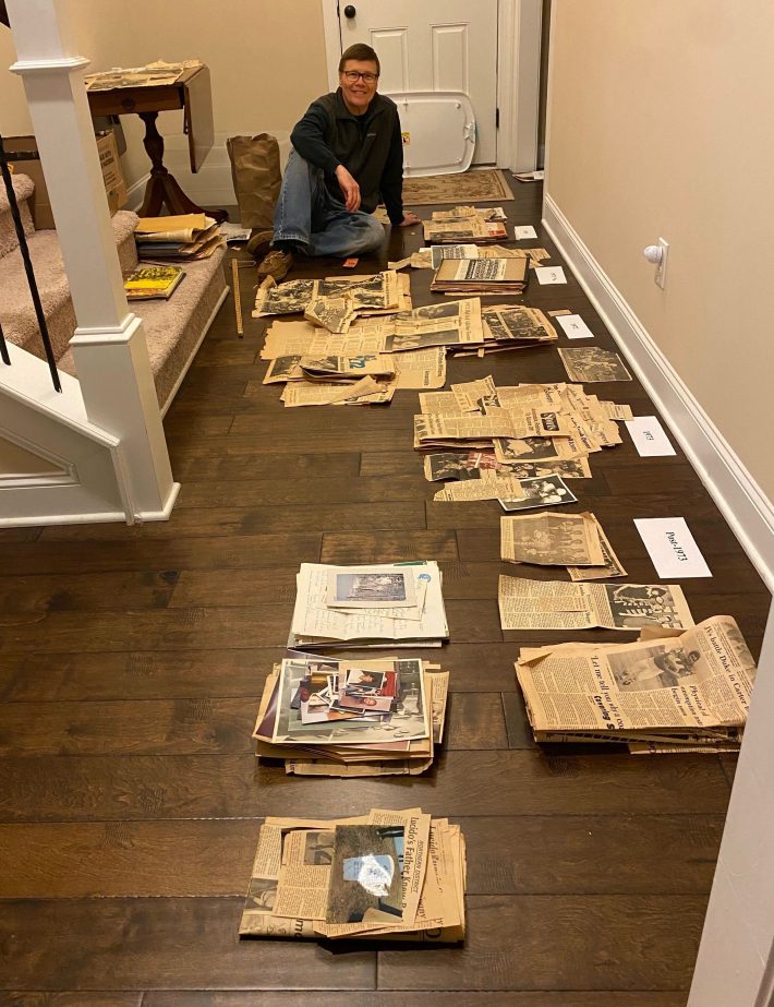 Bob Grimesey on the floor surrounded by hundreds of clippings from Lucido's mom's scrapbooks in April of 2024.