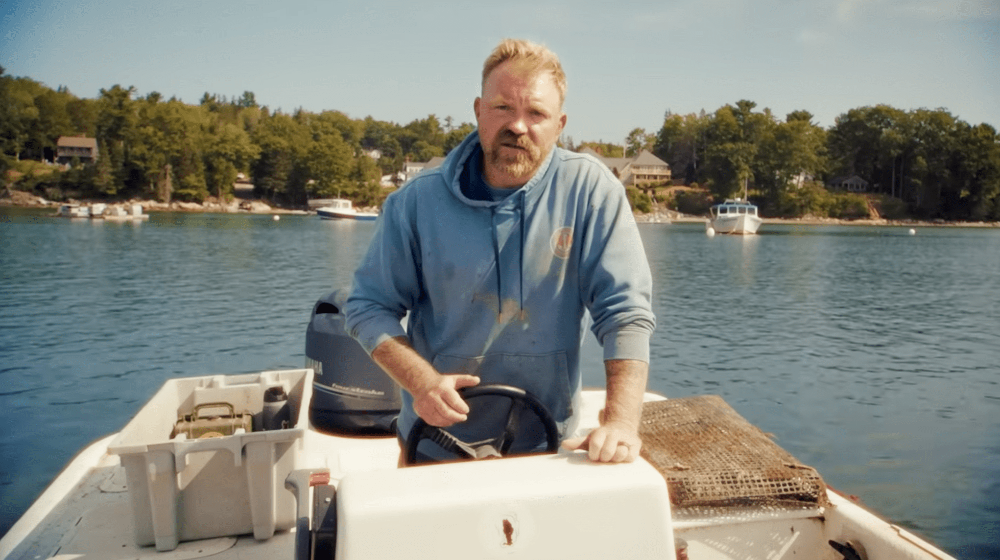 Maine Senate candidate Graham Platner seen in a blue sweatshirt on a boat in an image from his campaign ad. He has red hair and a beard.