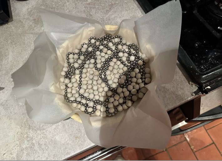 pie on the counter with parchment paper and baking beads inside