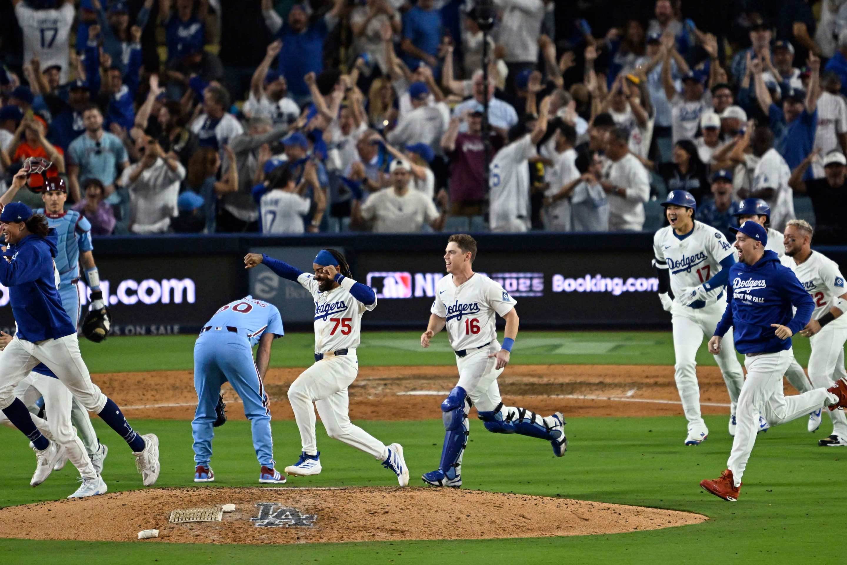 Los Angeles Dodgers celebrate as they run past relief pitcher Orion Kerkering #50 of the Philadelphia Phillies.