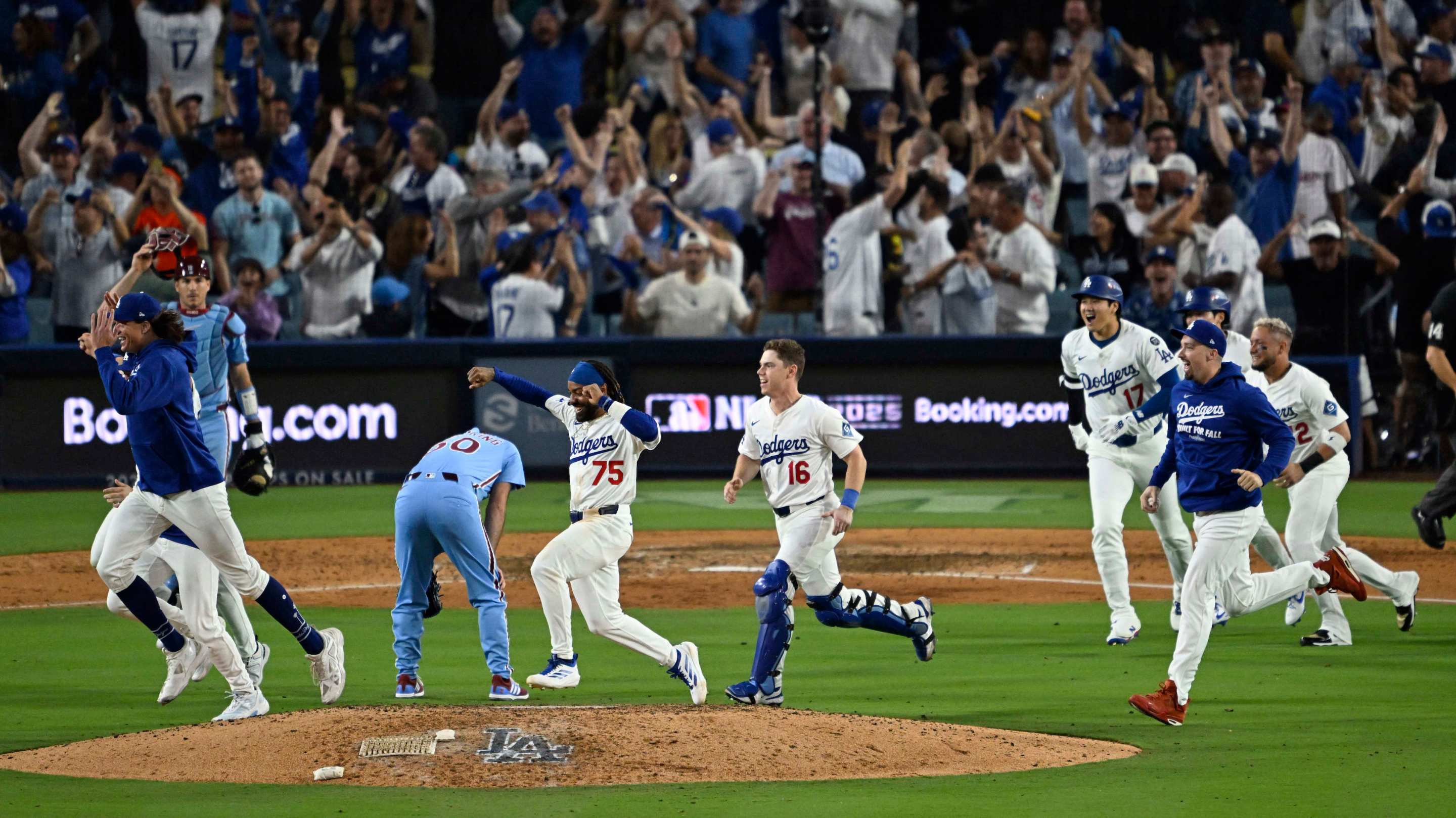 Los Angeles Dodgers celebrate as they run past relief pitcher Orion Kerkering #50 of the Philadelphia Phillies.