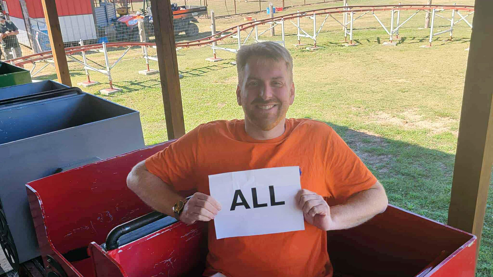 Rick Mathews holding a sign that says "ALL" on a children's coaster to say he has all of them.